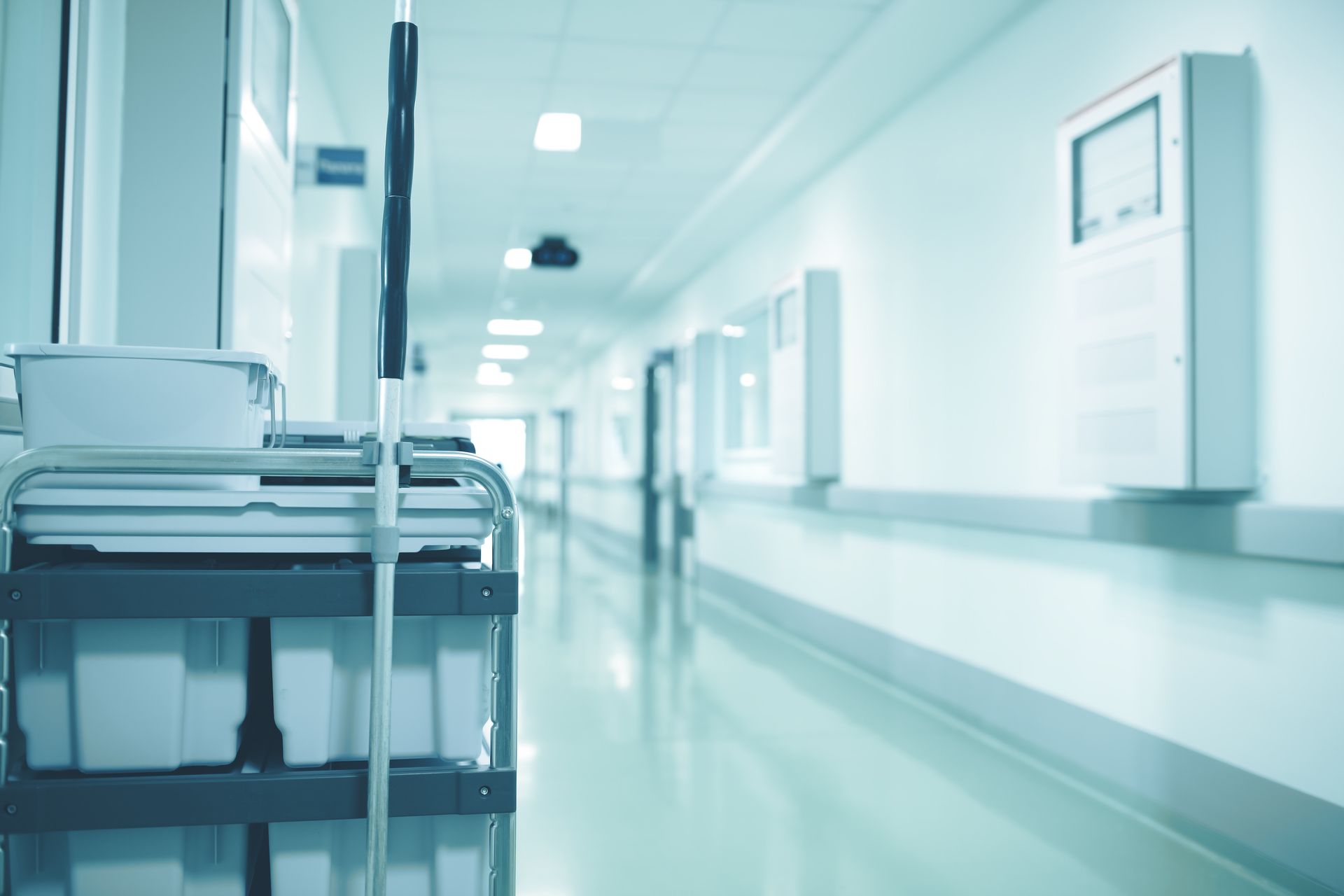 Hospital hallway with cleaning cart in foreground, leading to the light at the end.