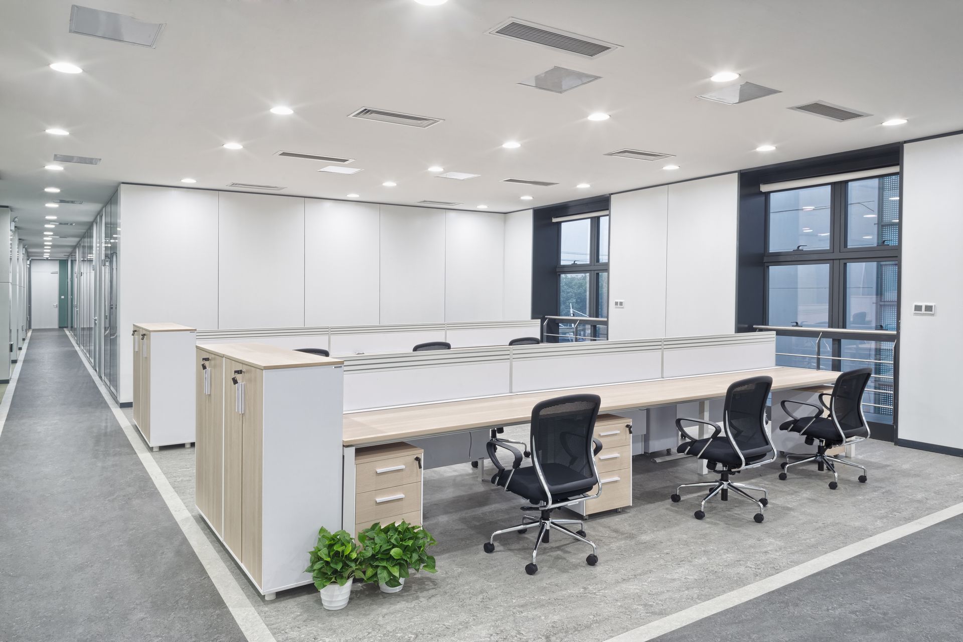 Bright office interior with cubicles, chairs, and windows. White walls, grey carpet. Bright office interior with cubicles, chairs, and windows. White walls, grey carpet.
