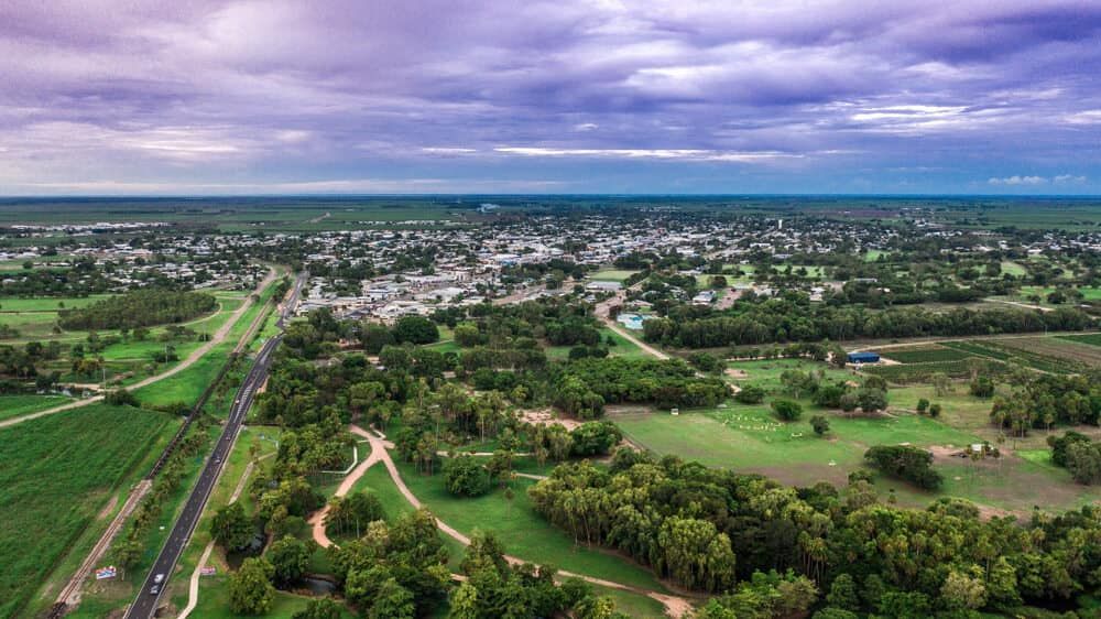 An Aerial View Of A Small Town Surrounded By Trees And Fields — Lynda Ross Marriage Celebrant In Ayr, QLD