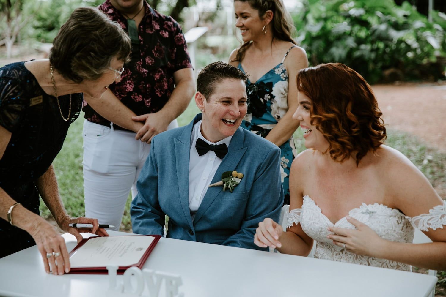 A Marriage Celebrant Signs Marriage Certificate With Smiling Groom — Lynda Ross Marriage Celebrant In Alice River, QLD
