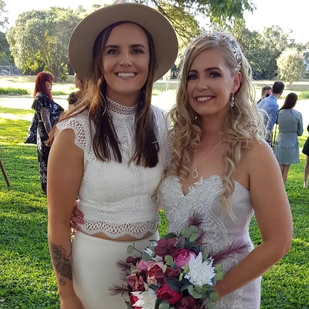 Two Women In Wedding Dresses Are Posing For A Picture In A Park — Lynda Ross Marriage Celebrant In Alice River, QLD
