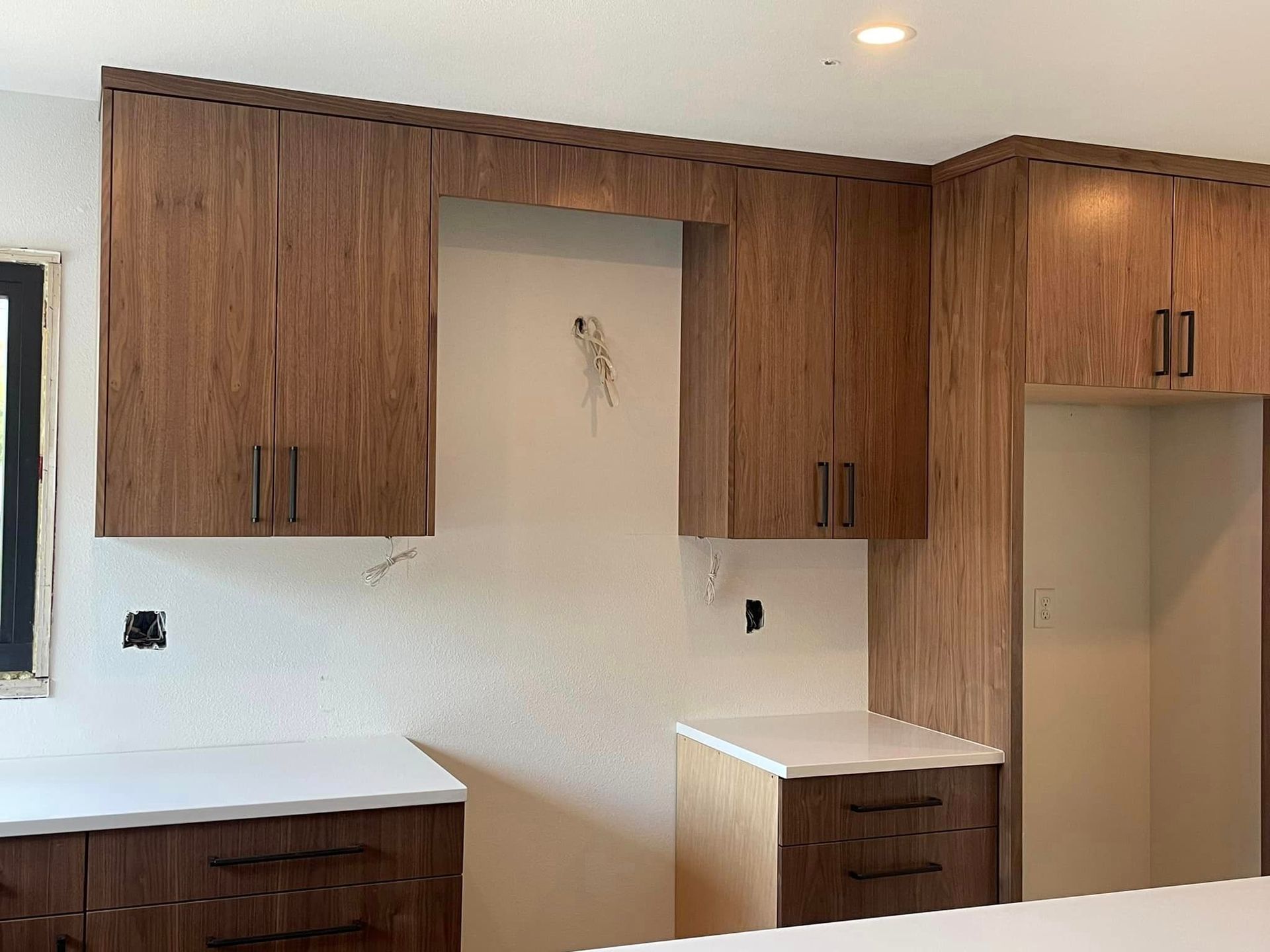 A kitchen with wooden cabinets and white counter tops.