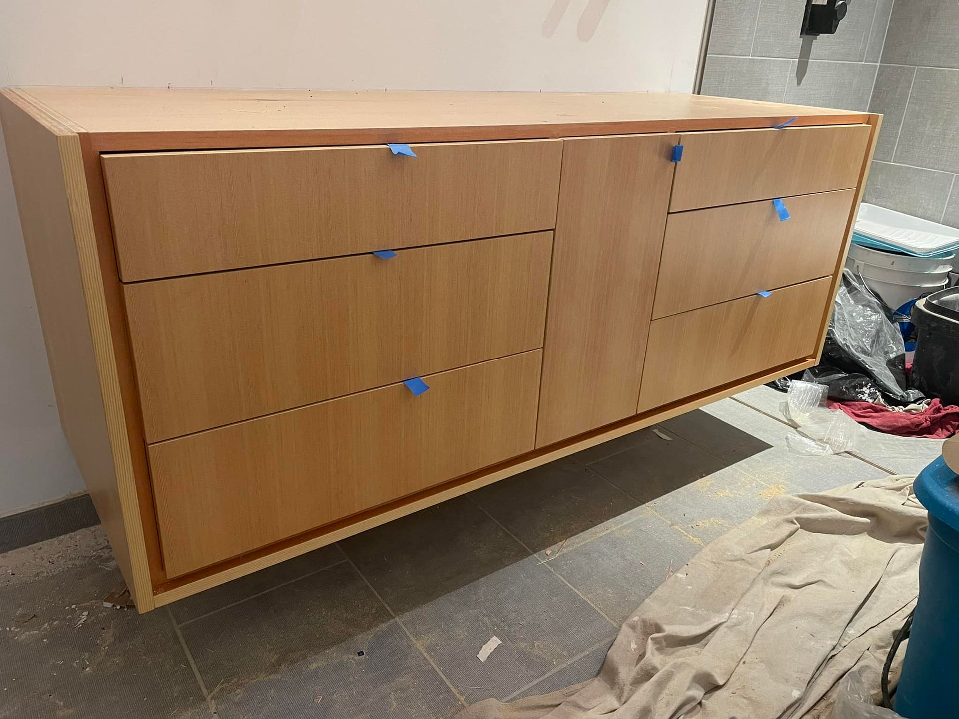 A wooden dresser is sitting on a tiled floor in a room.