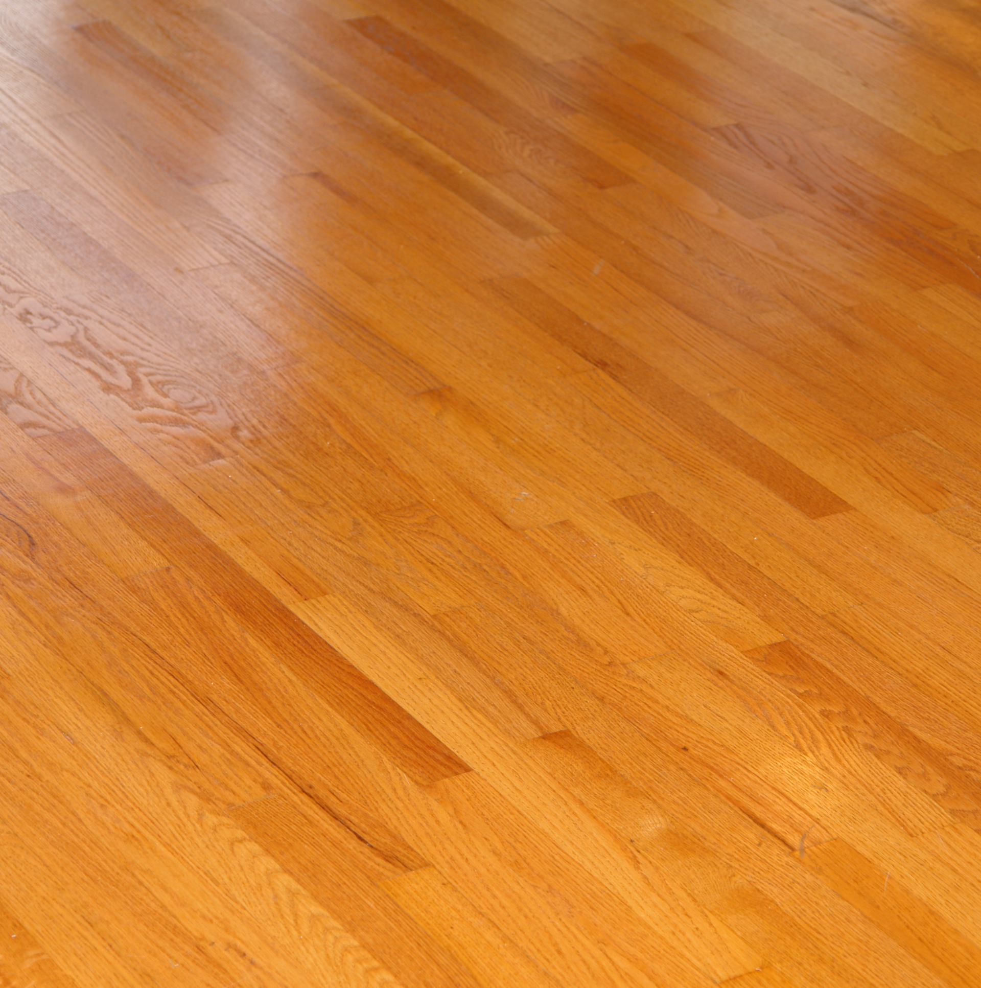 Close-up of smooth, light brown hardwood flooring with visible wood grain patterns running diagonally.