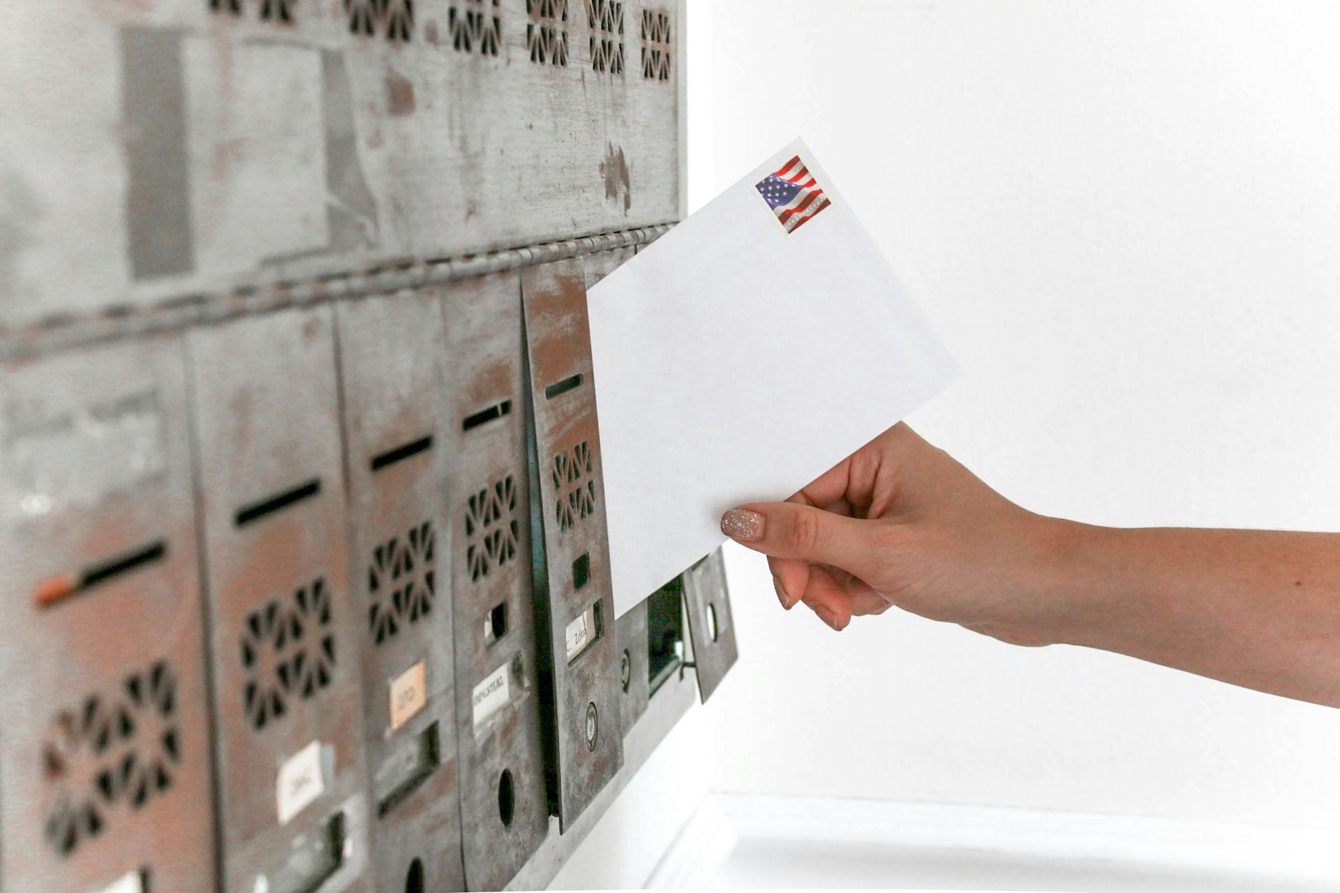 A person is putting an envelope in a mailbox with an american flag on it