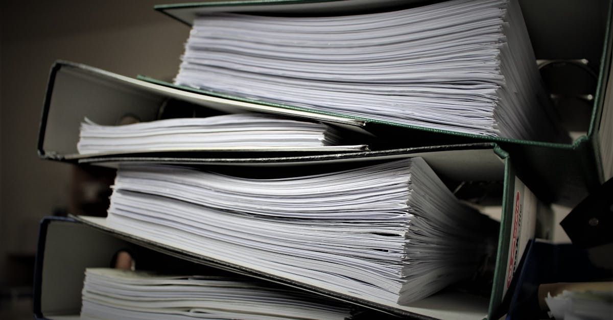 A stack of binders filled with papers is sitting on top of each other.