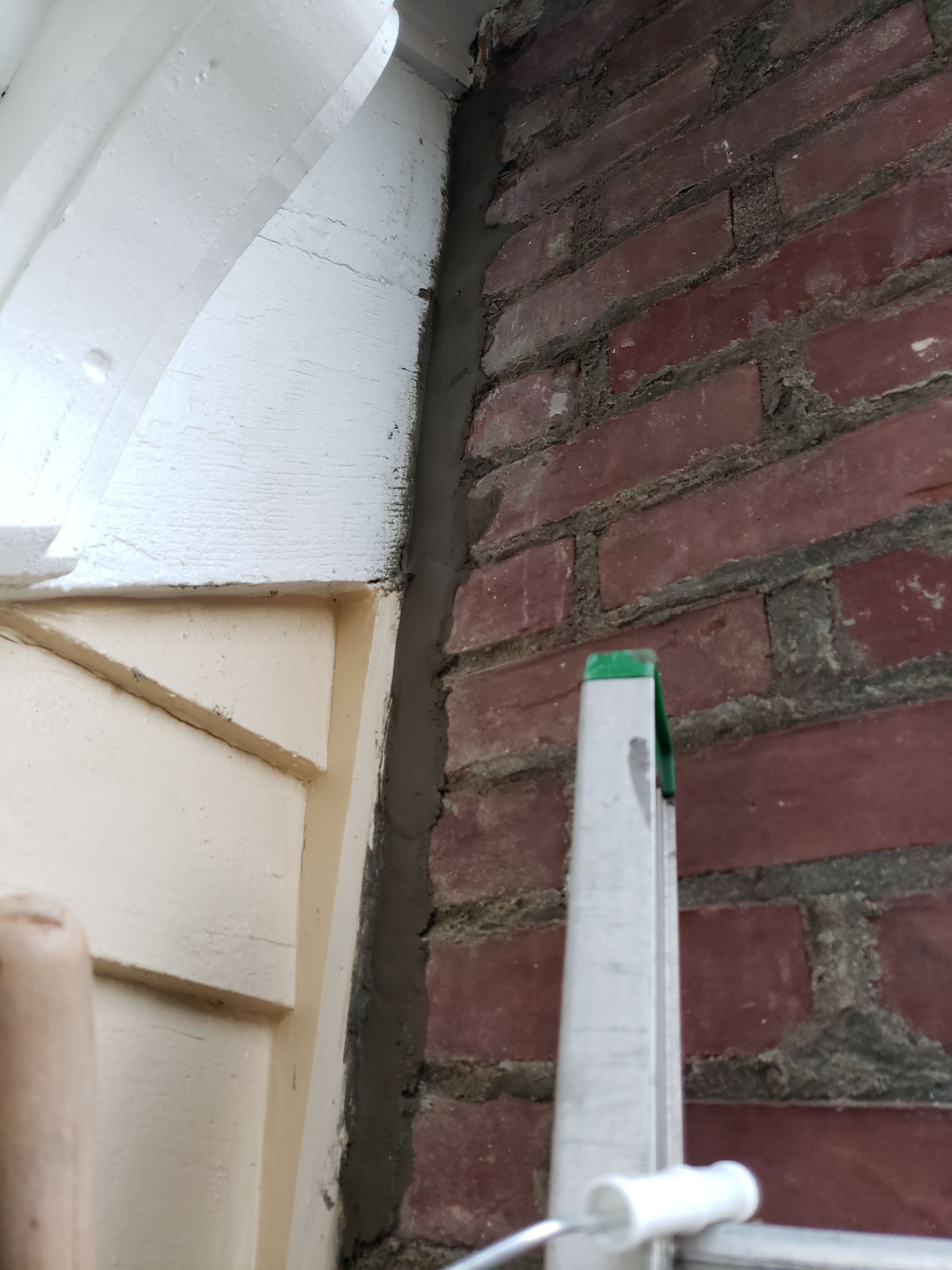 A ladder is leaning against a brick wall next to a door.