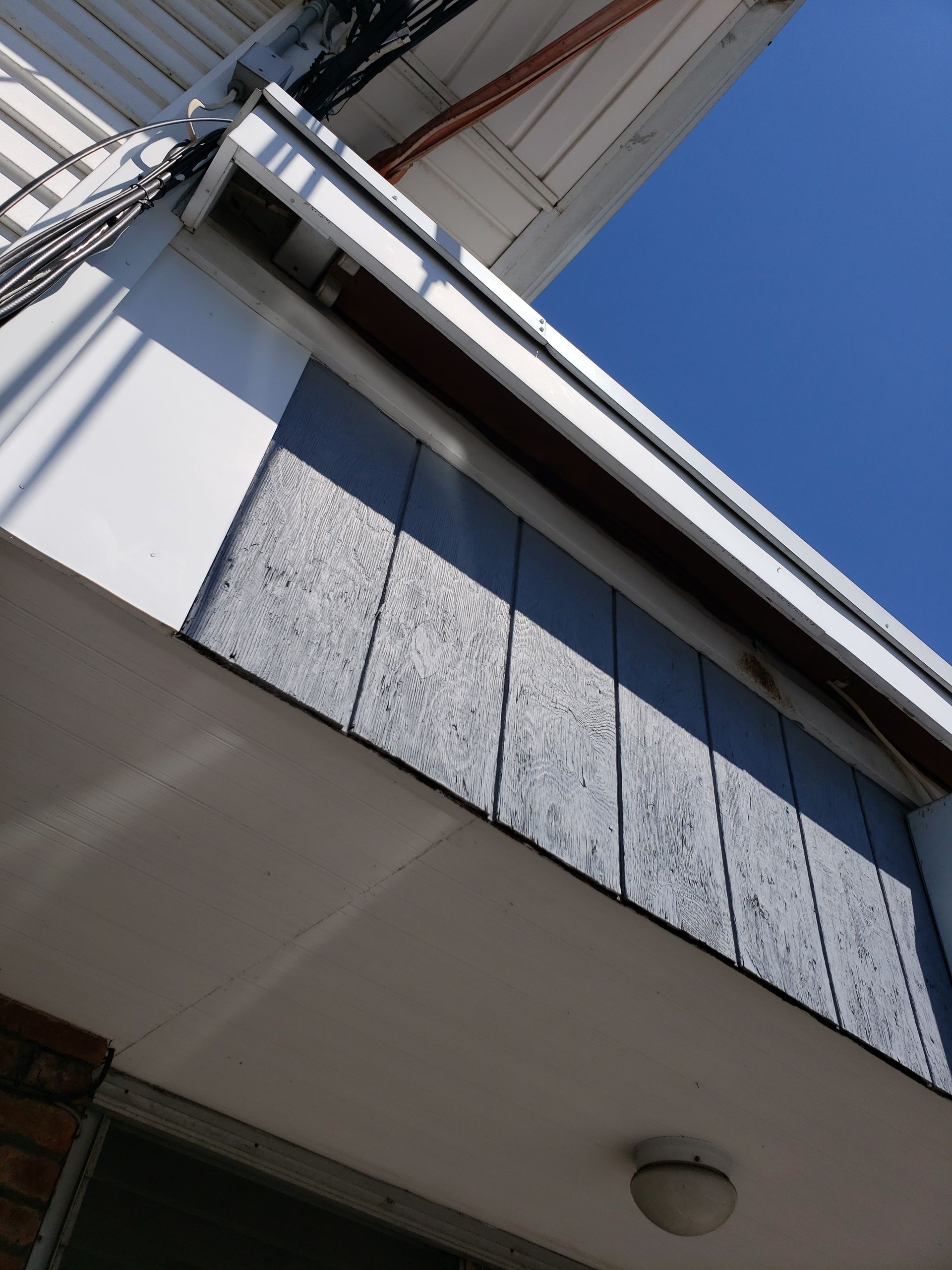 Looking up at the roof of a building with a blue sky in the background