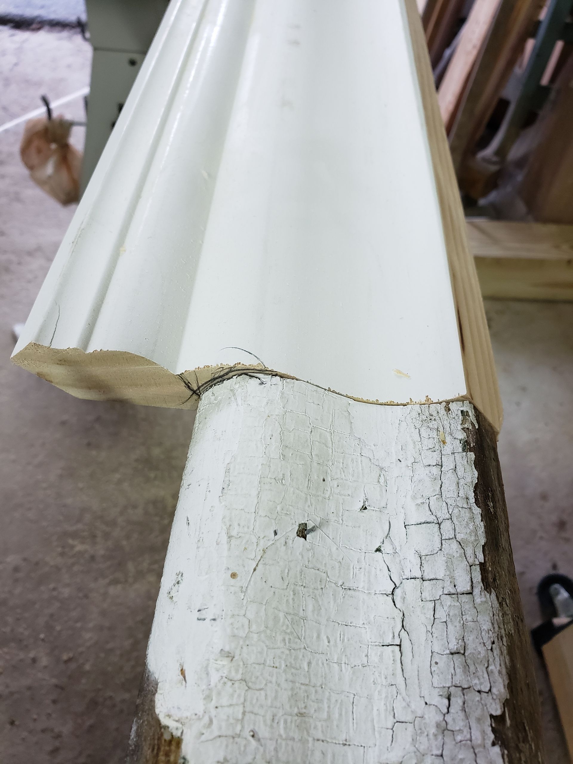 A piece of white molding is sitting on a piece of wood.