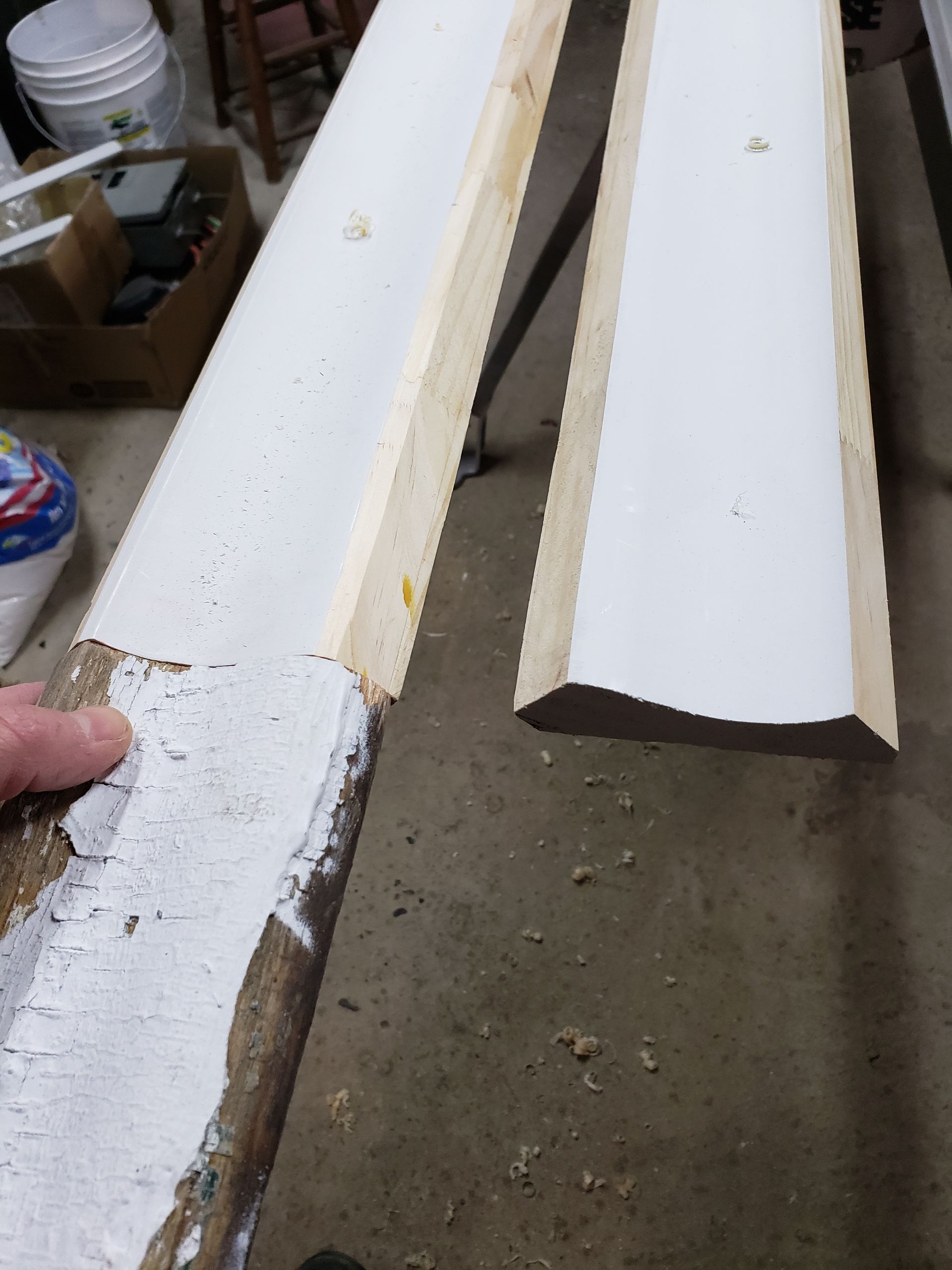 A person is holding a piece of wood that has been painted white