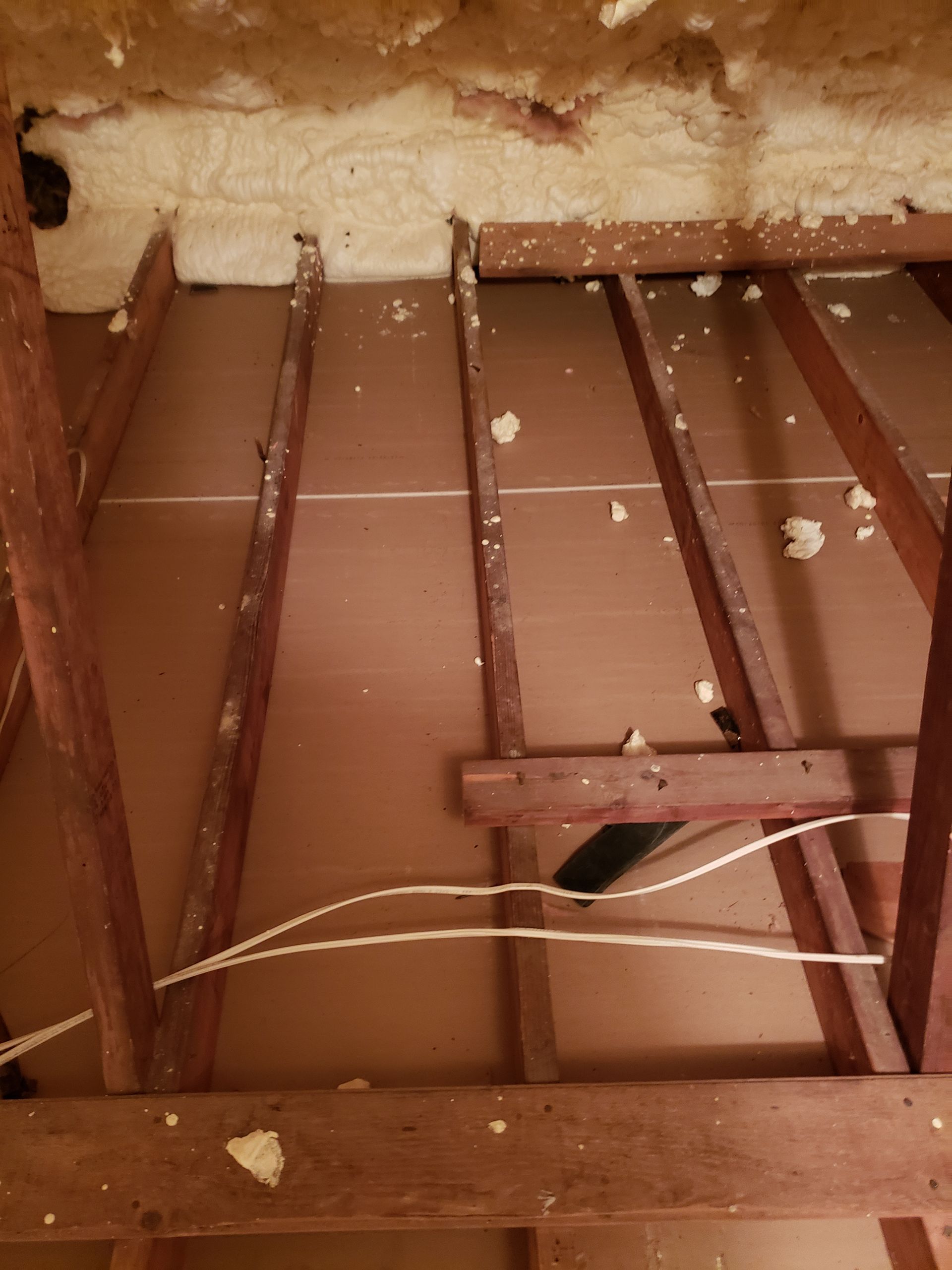 The ceiling of a room with wooden beams and foam on it.
