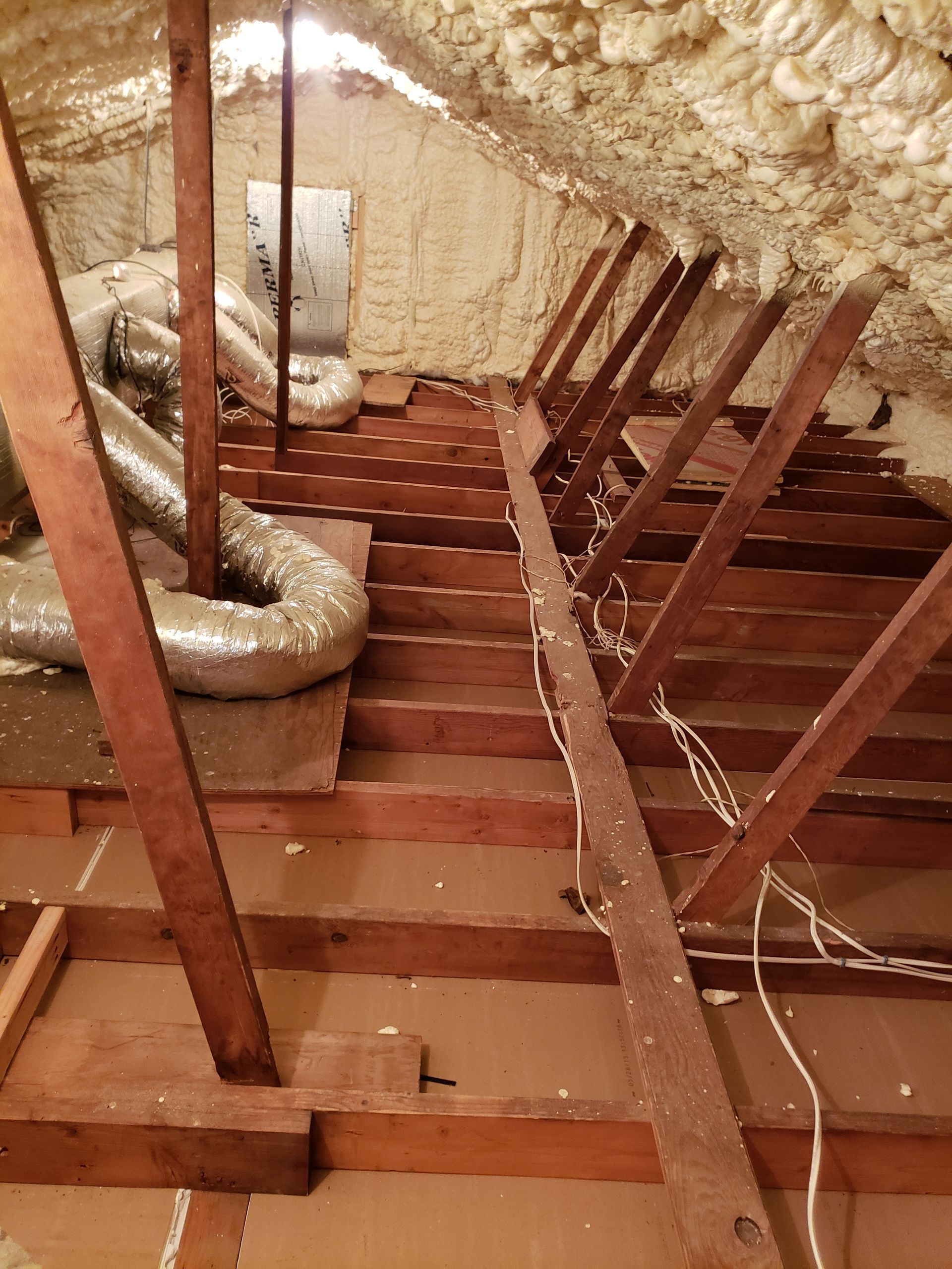 An attic with a lot of wooden beams and ducts
