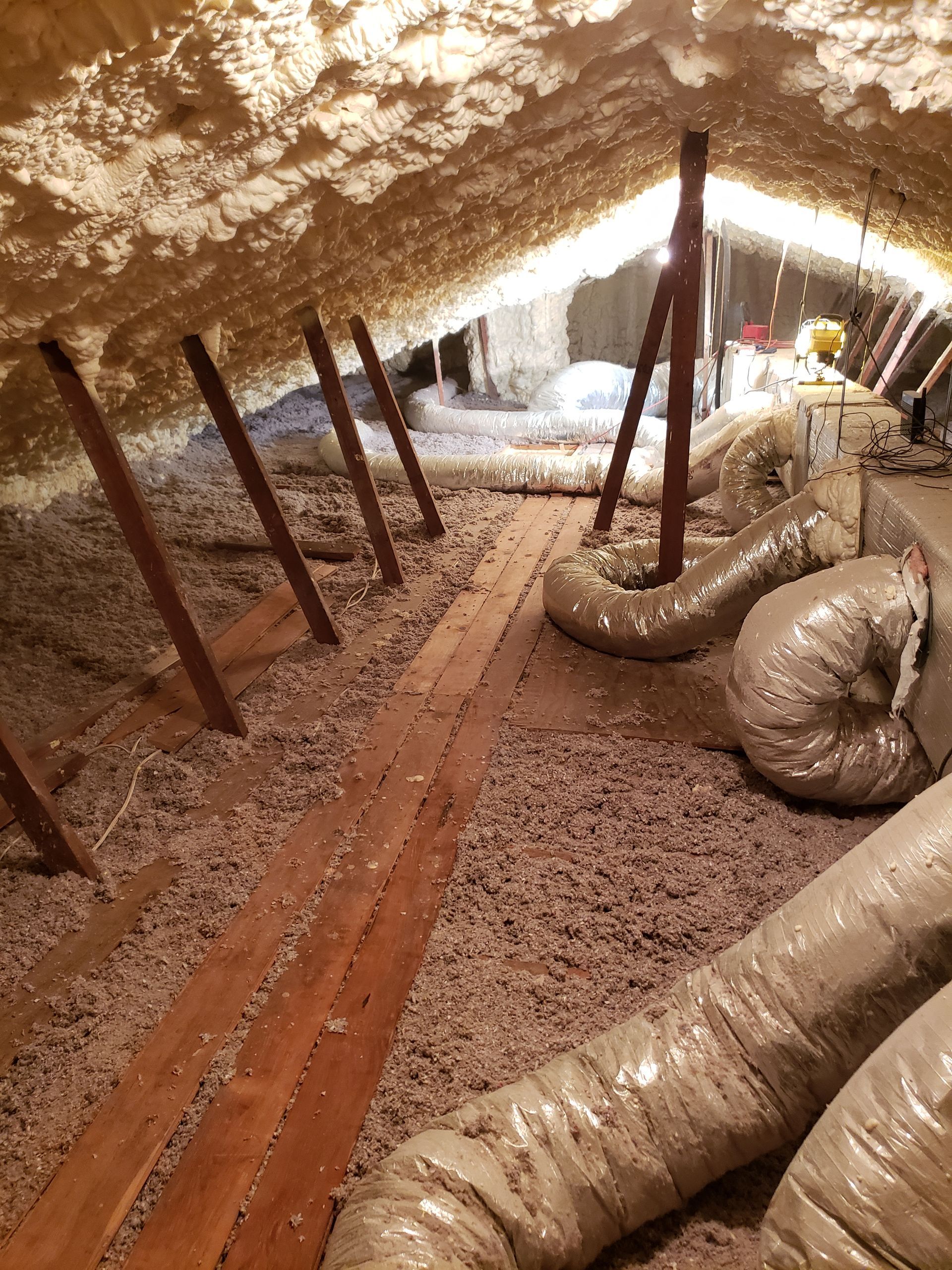 An attic with a lot of insulation and ducts.