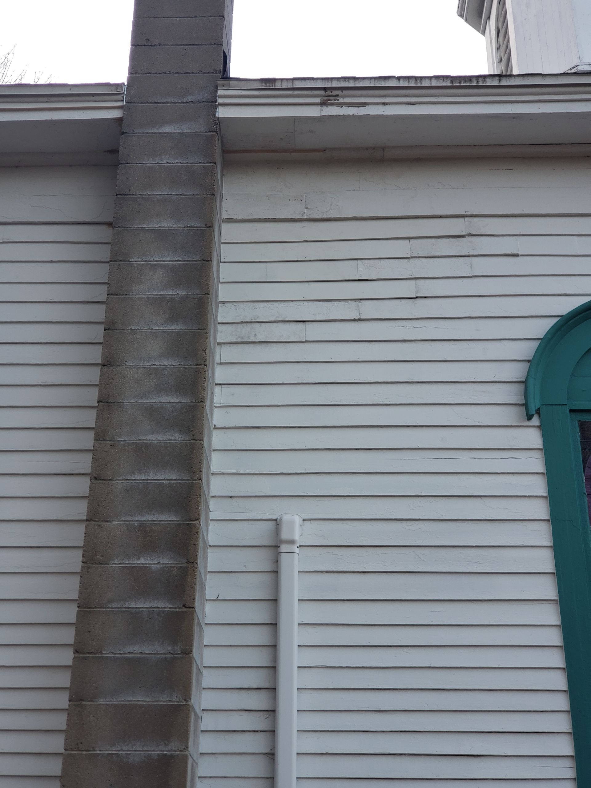 A white house with a chimney on the side of it