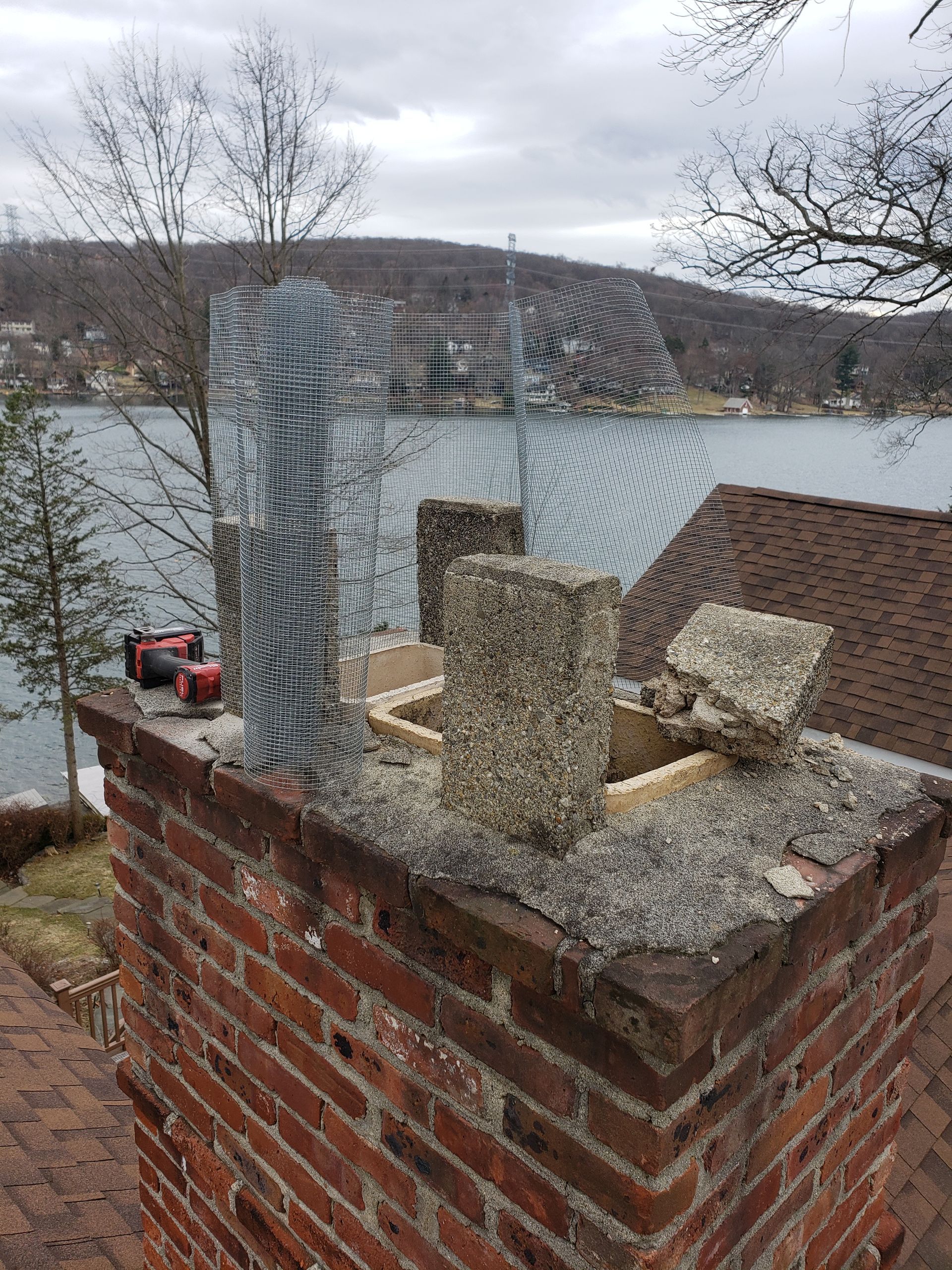 A brick chimney is sitting on top of a brick roof next to a body of water.