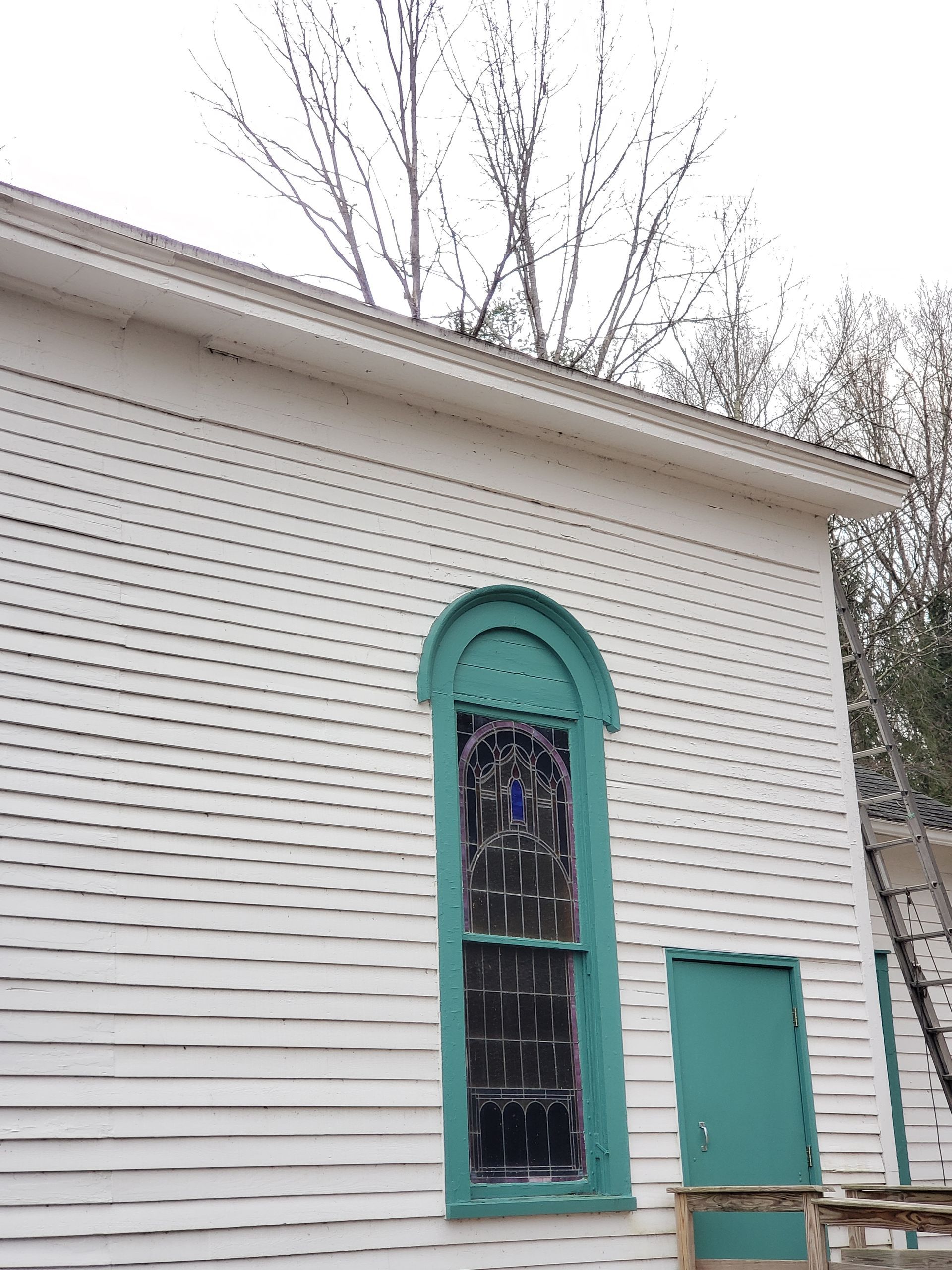 A white building with a green door and a stained glass window.