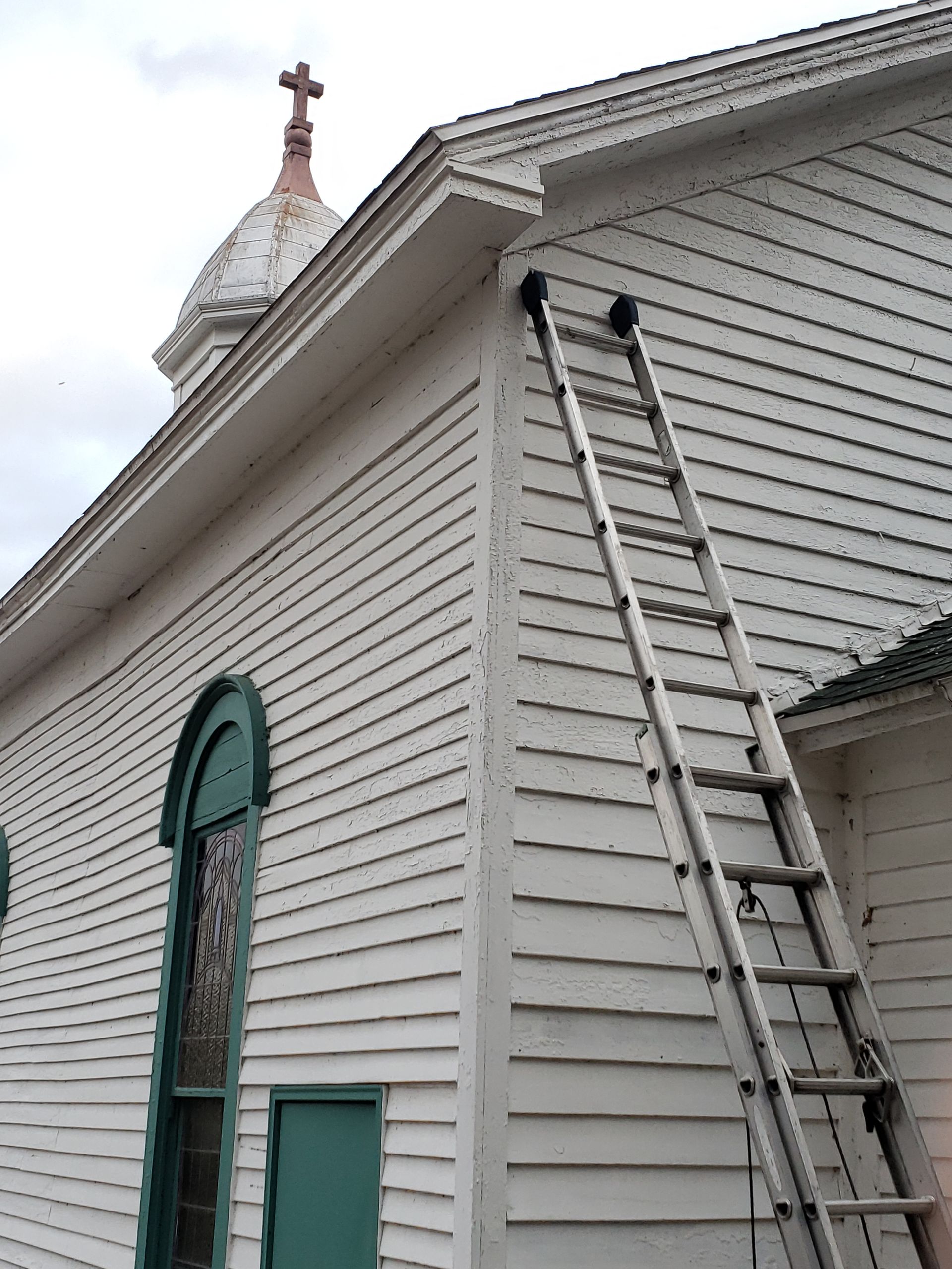 A ladder is leaning against the side of a church.