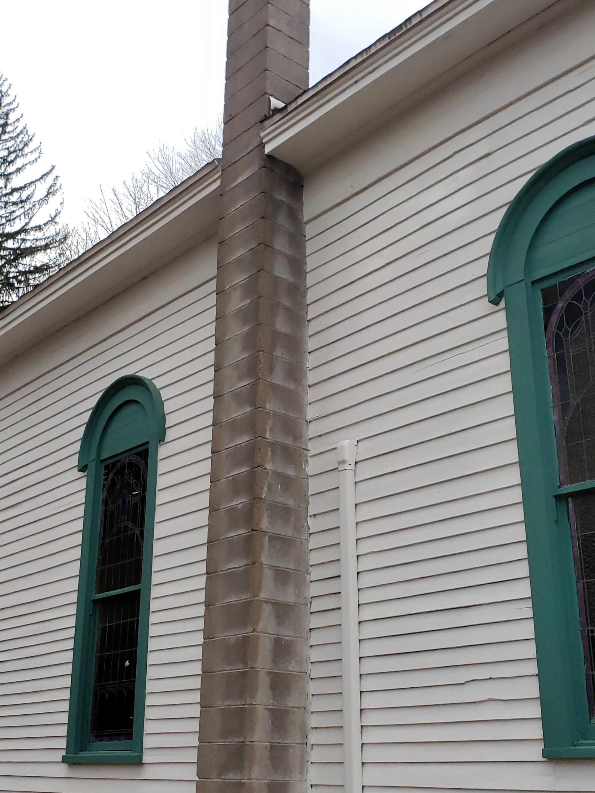 A white house with green windows and a chimney