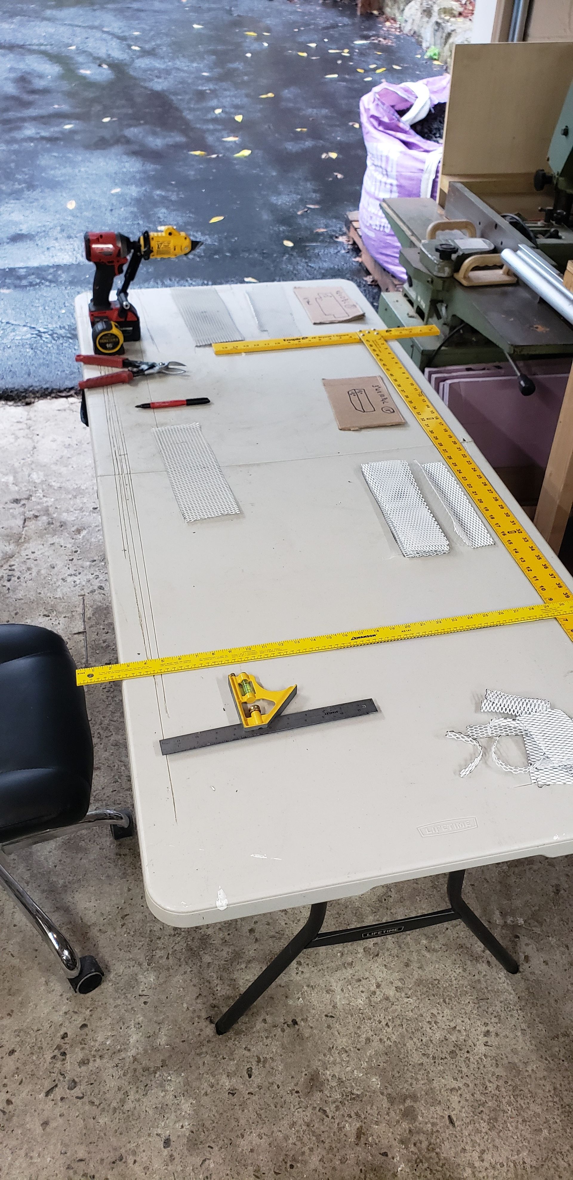 A table with a drill and measuring tape on it.