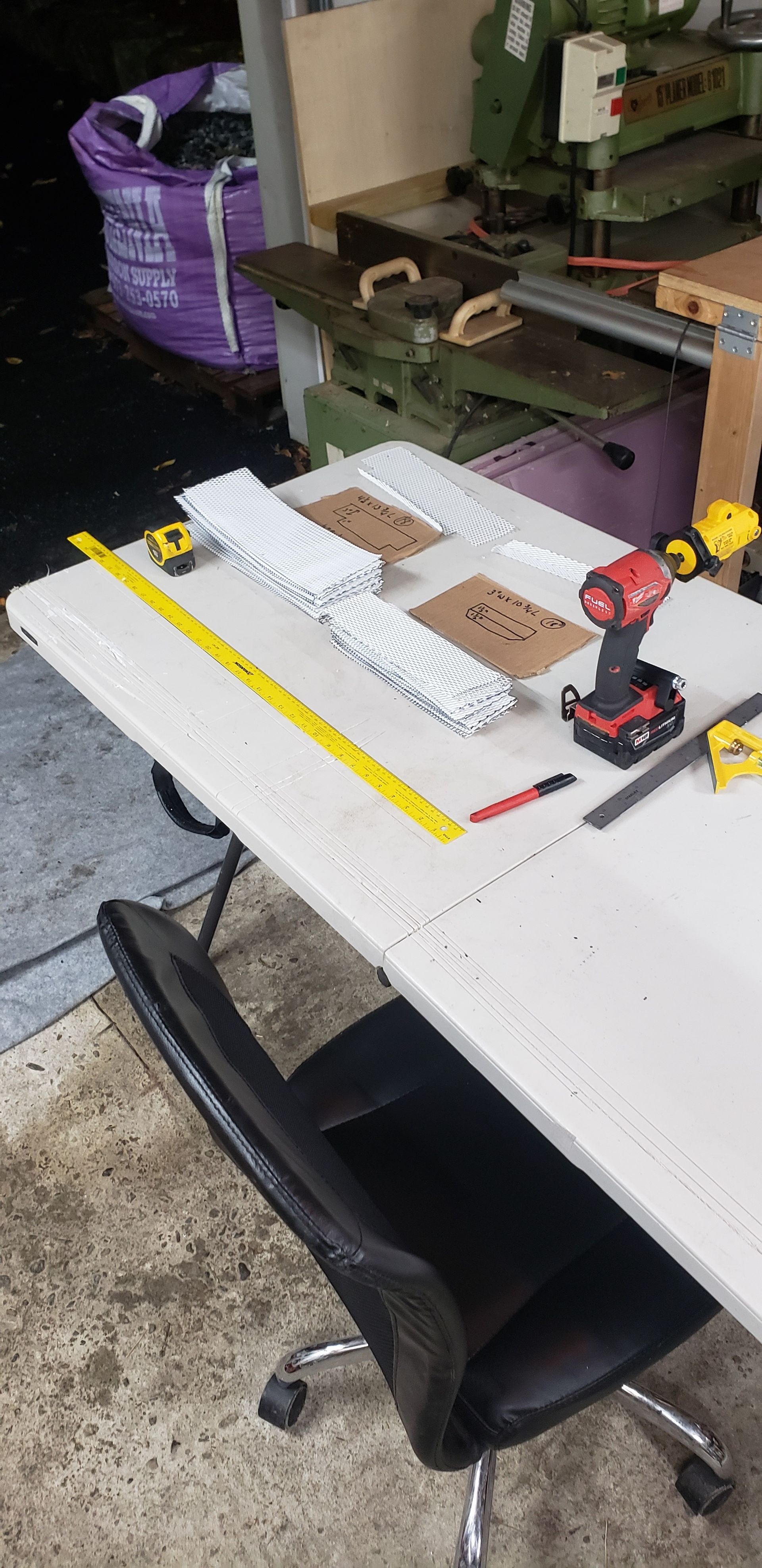 A table with a tape measure and a drill on it.