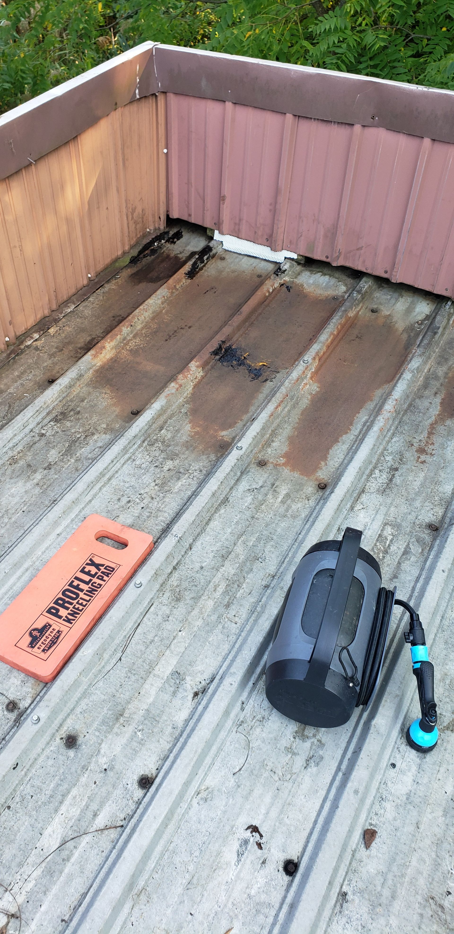A hose is sitting on top of a metal roof next to a sign.