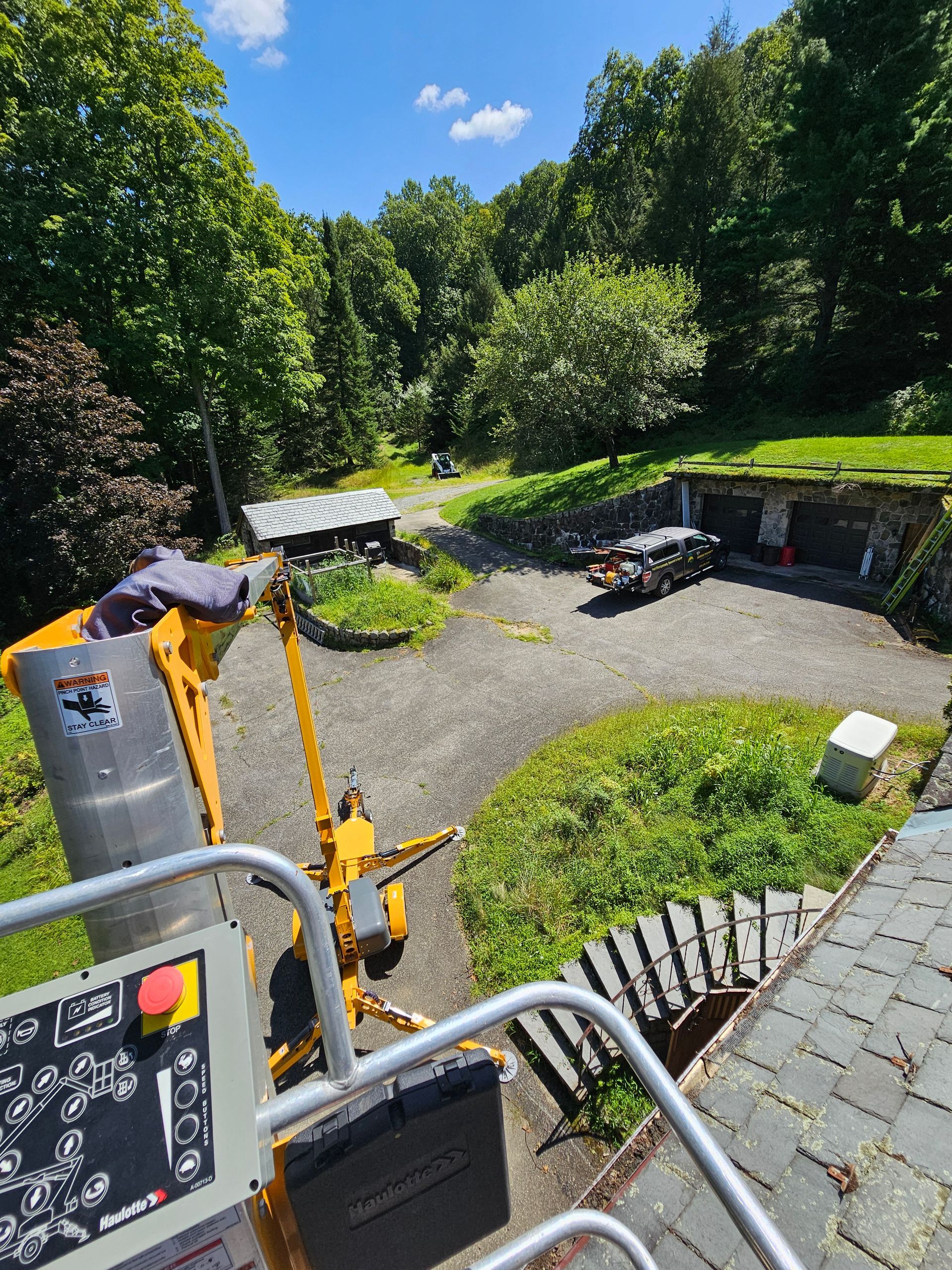 A yellow aerial lift is sitting on top of a roof.