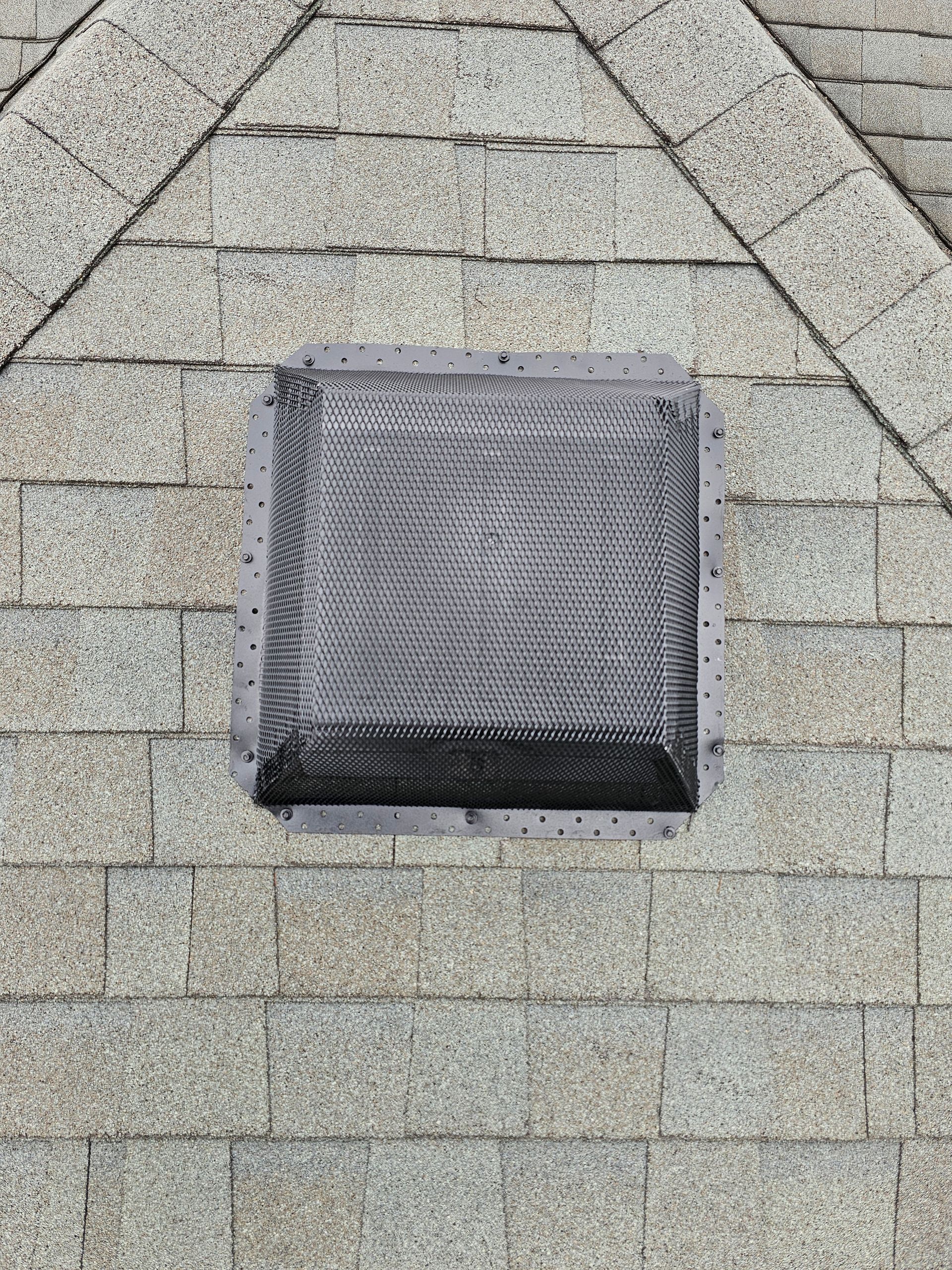 A square vent on the side of a brick building.