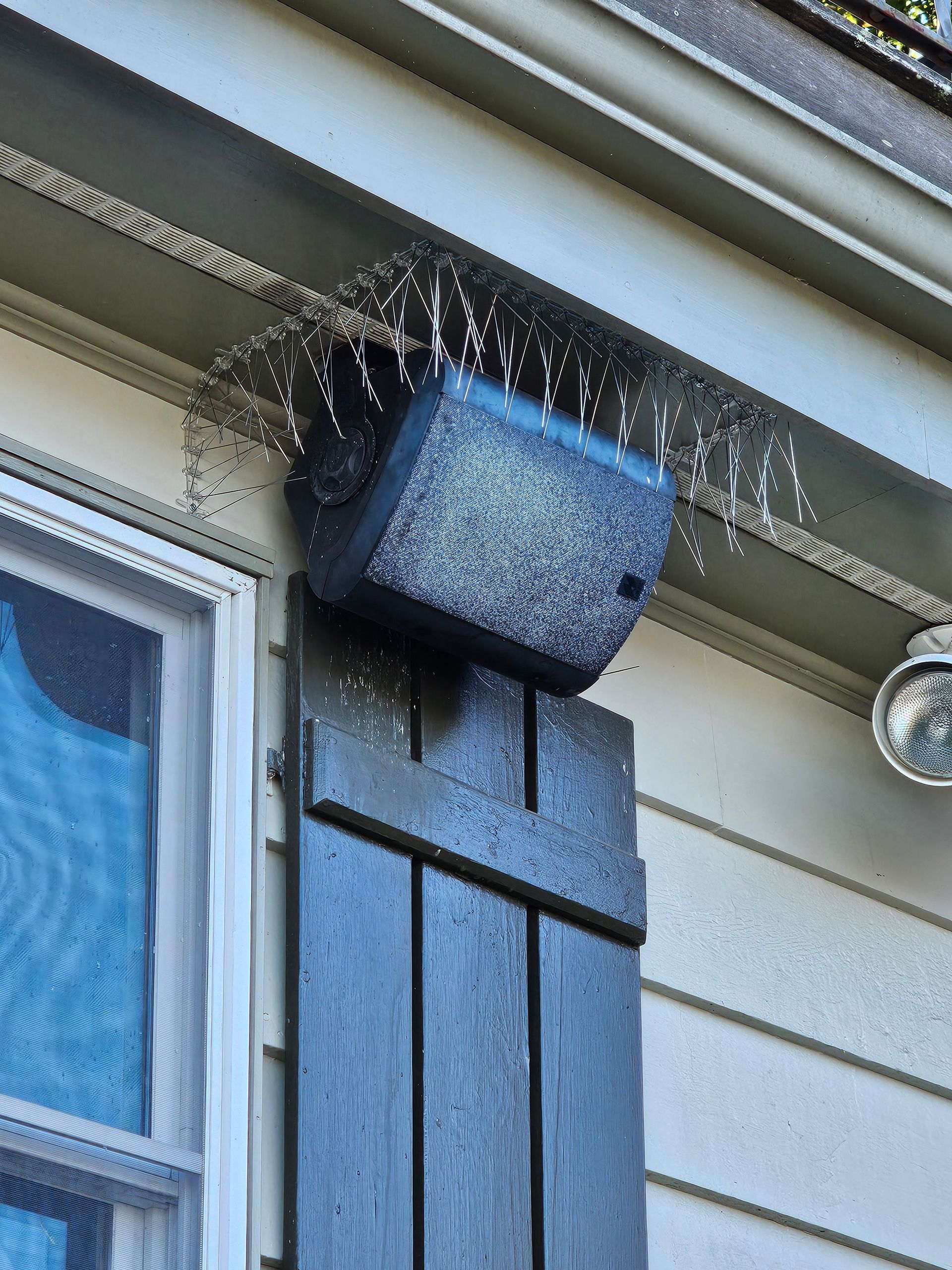 A window with black shutters and a light on it