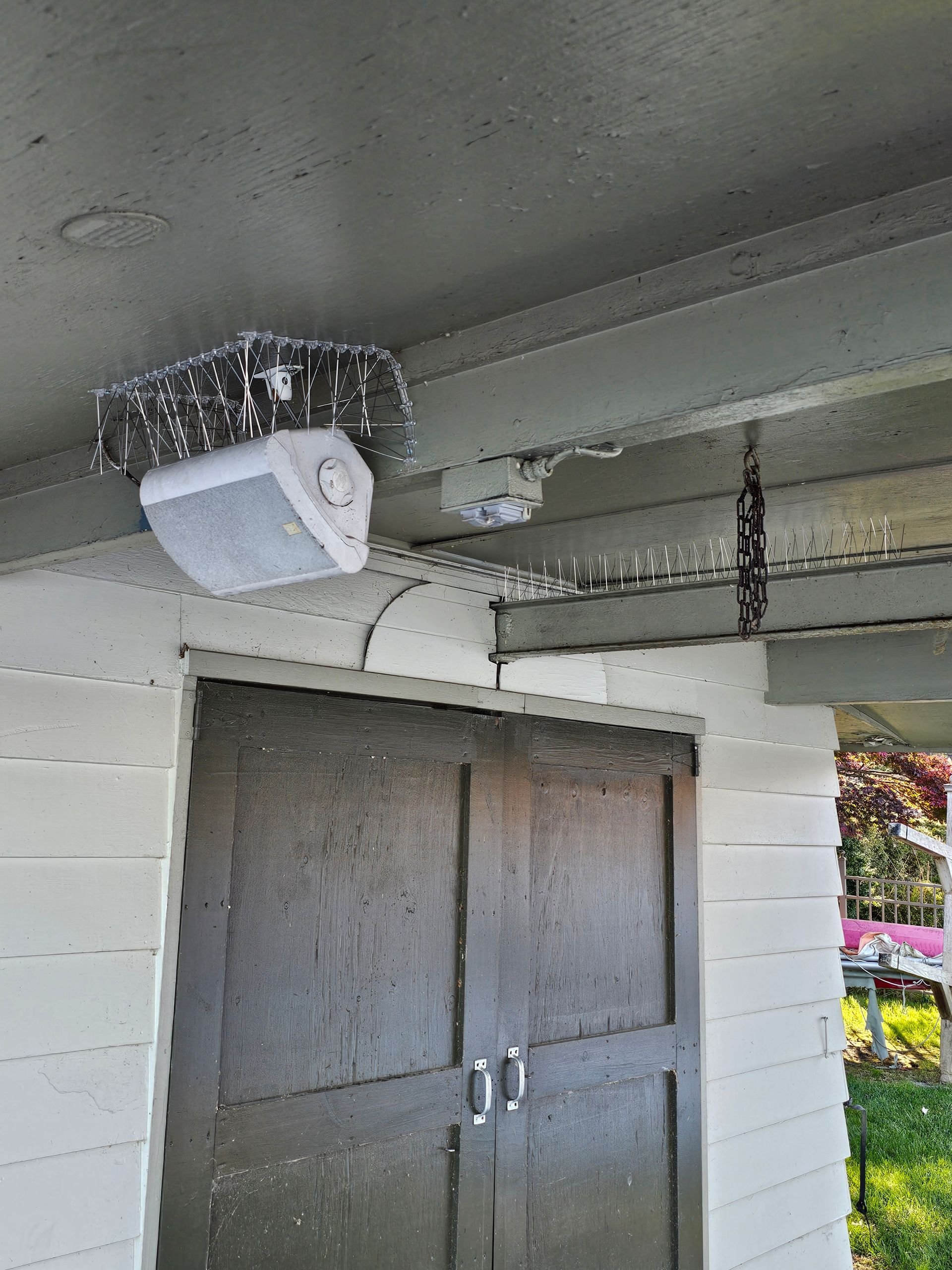 A speaker is hanging from the ceiling of a building next to a door.