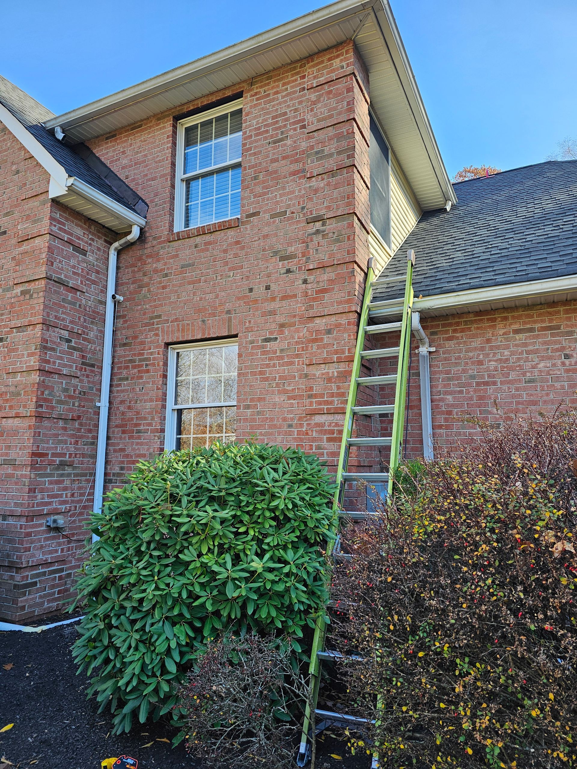 A ladder is sitting on the side of a brick house.