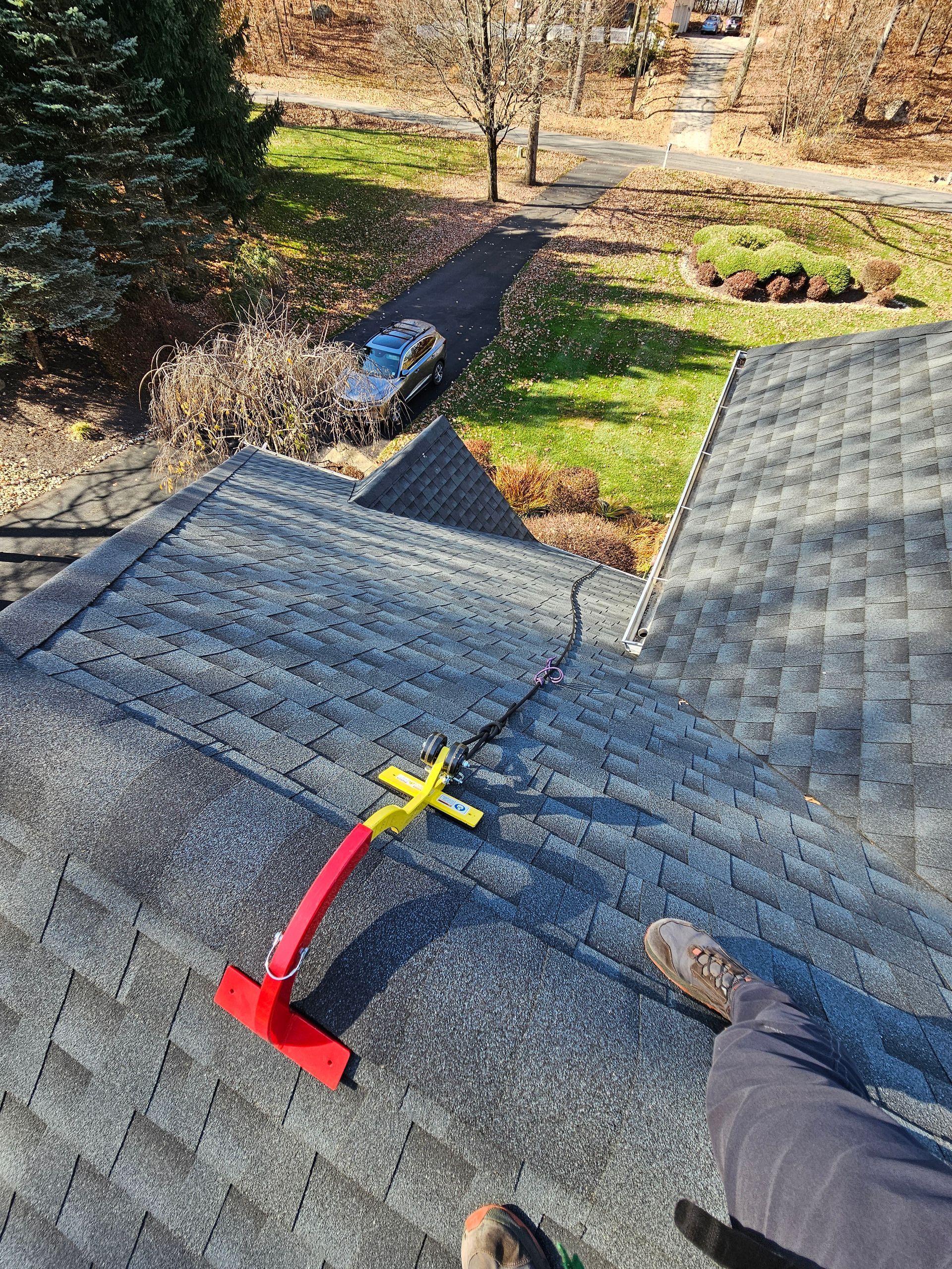 A person is standing on top of a roof with a tool on it.