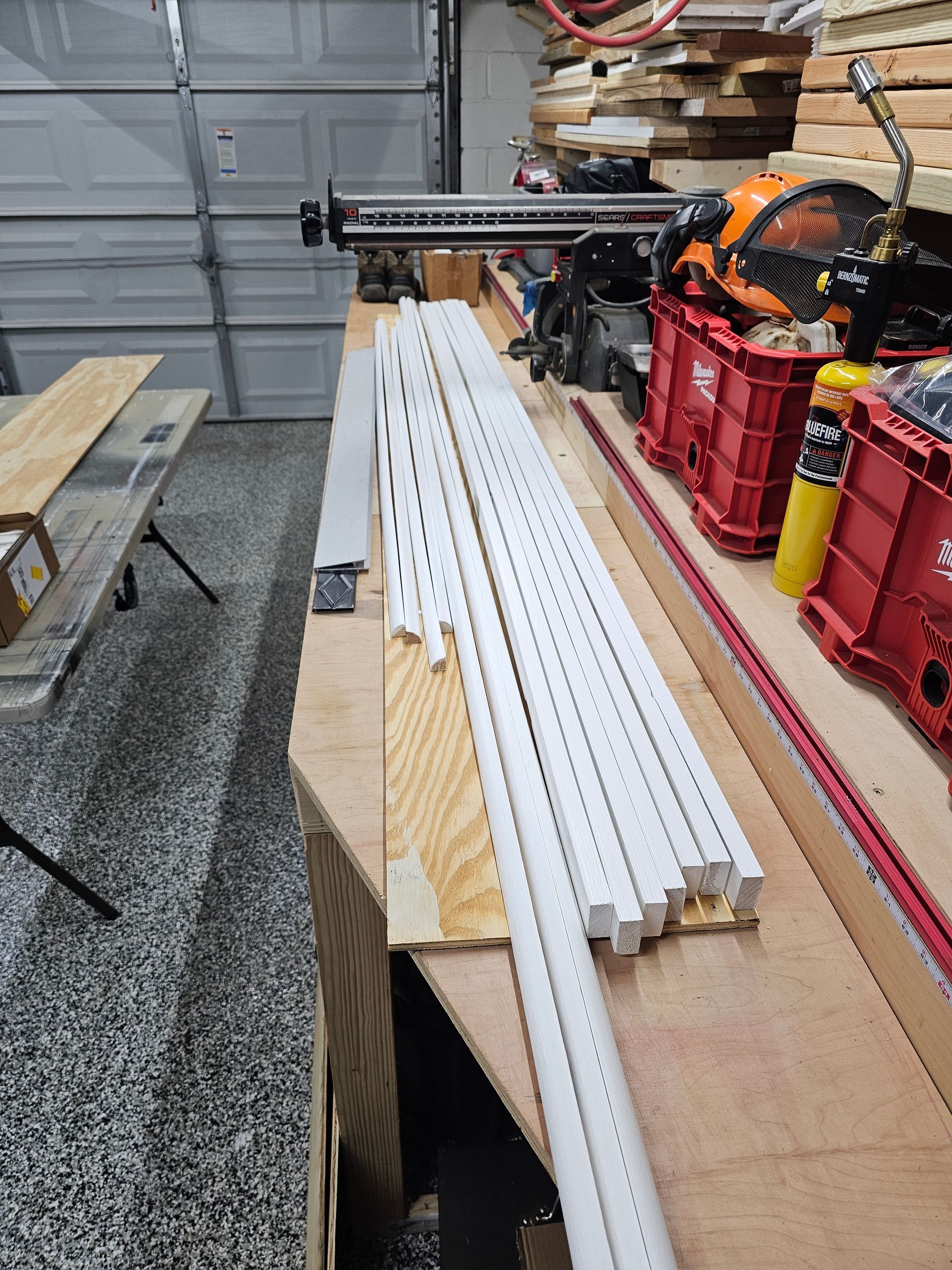 A bunch of white pipes are sitting on top of a wooden table in a garage.