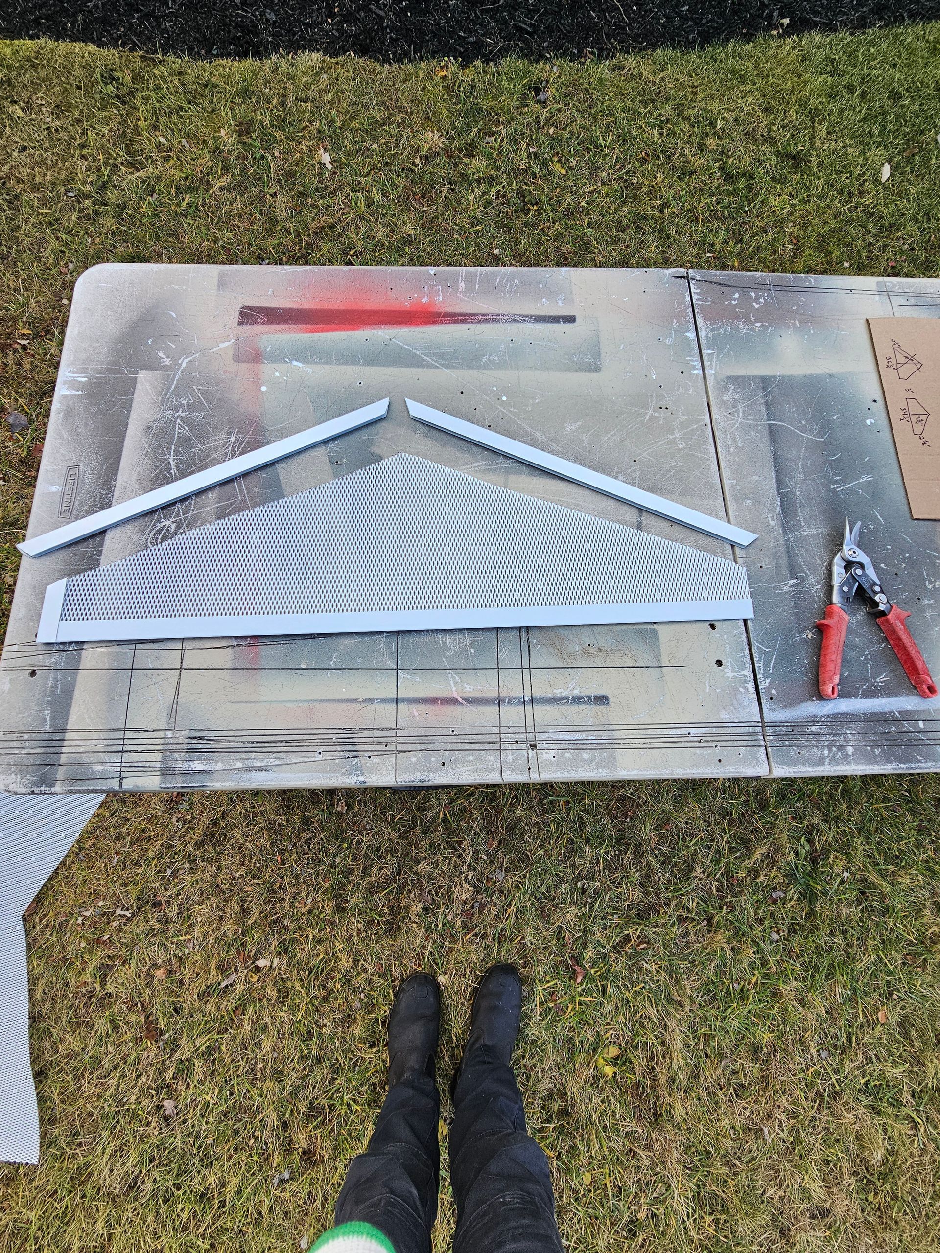 A person is standing next to a table with a piece of metal on it.