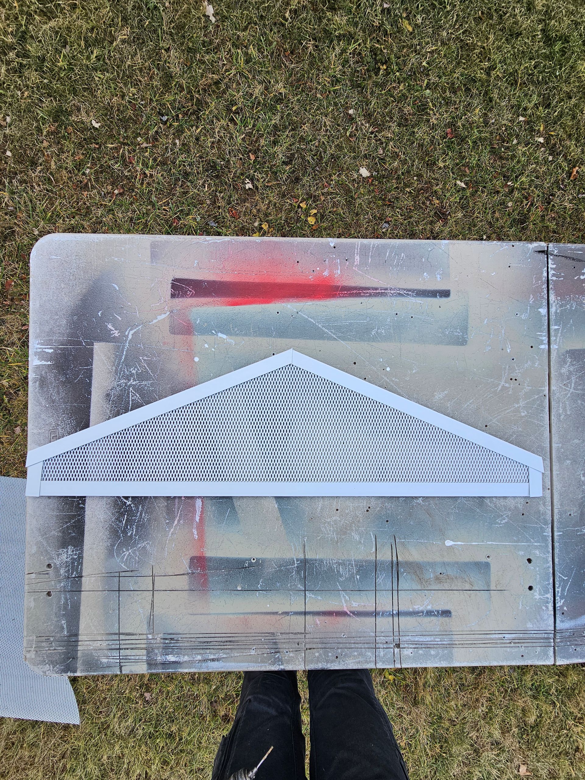 A person is standing next to a piece of metal that looks like a roof.