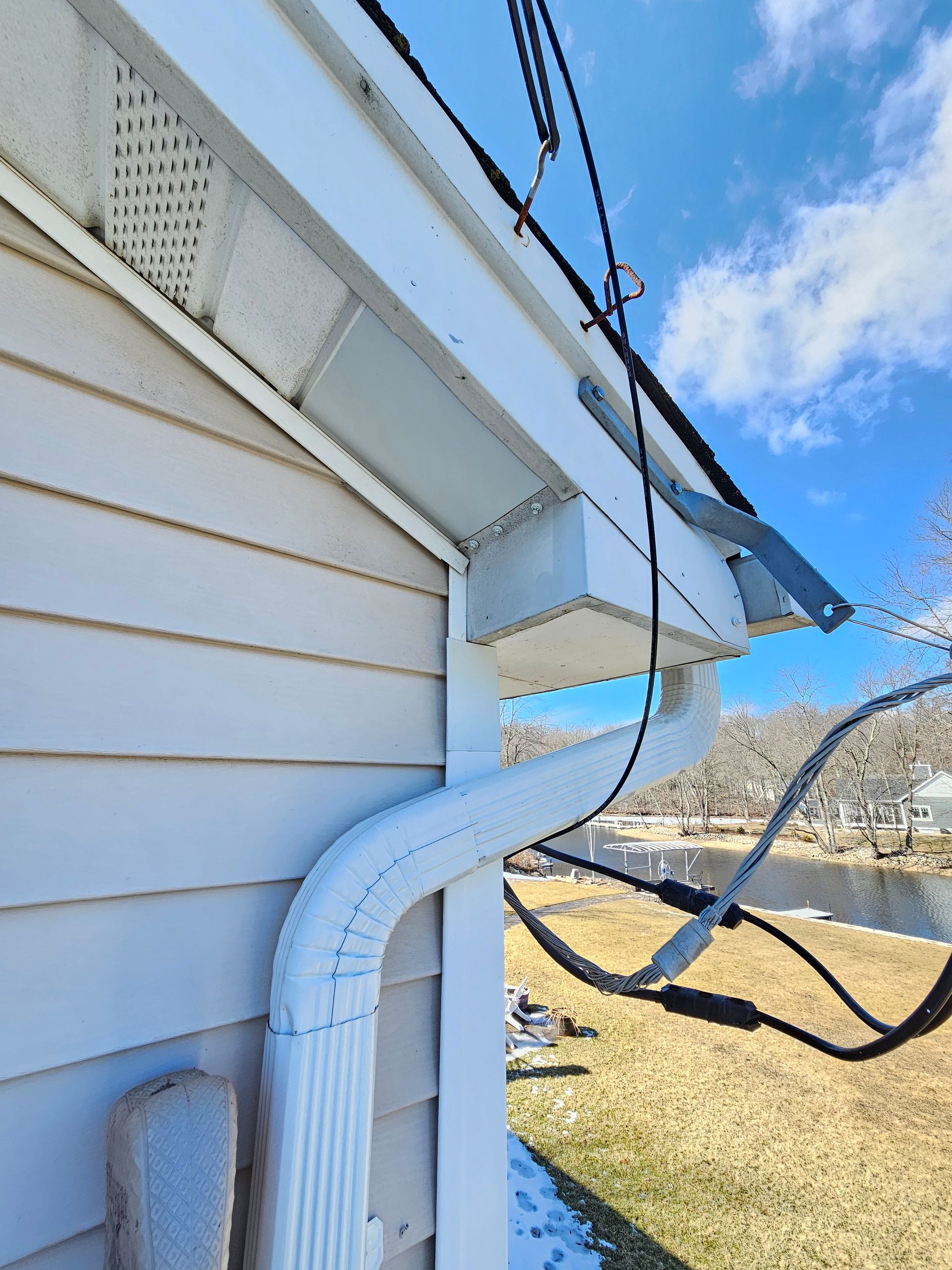 A white house with a gutter and power lines on it