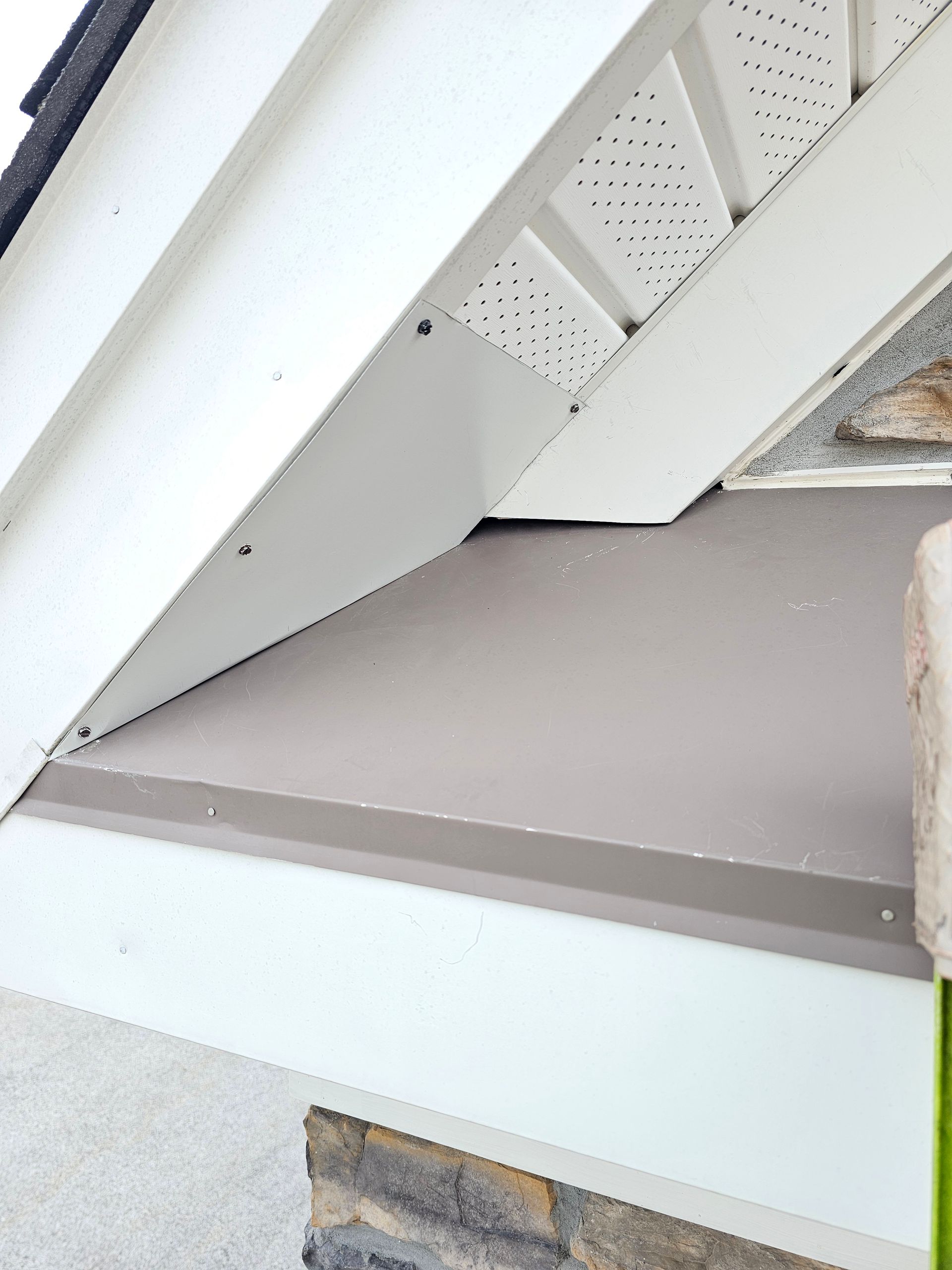 A close up of a porch with a white trim and a stone wall.