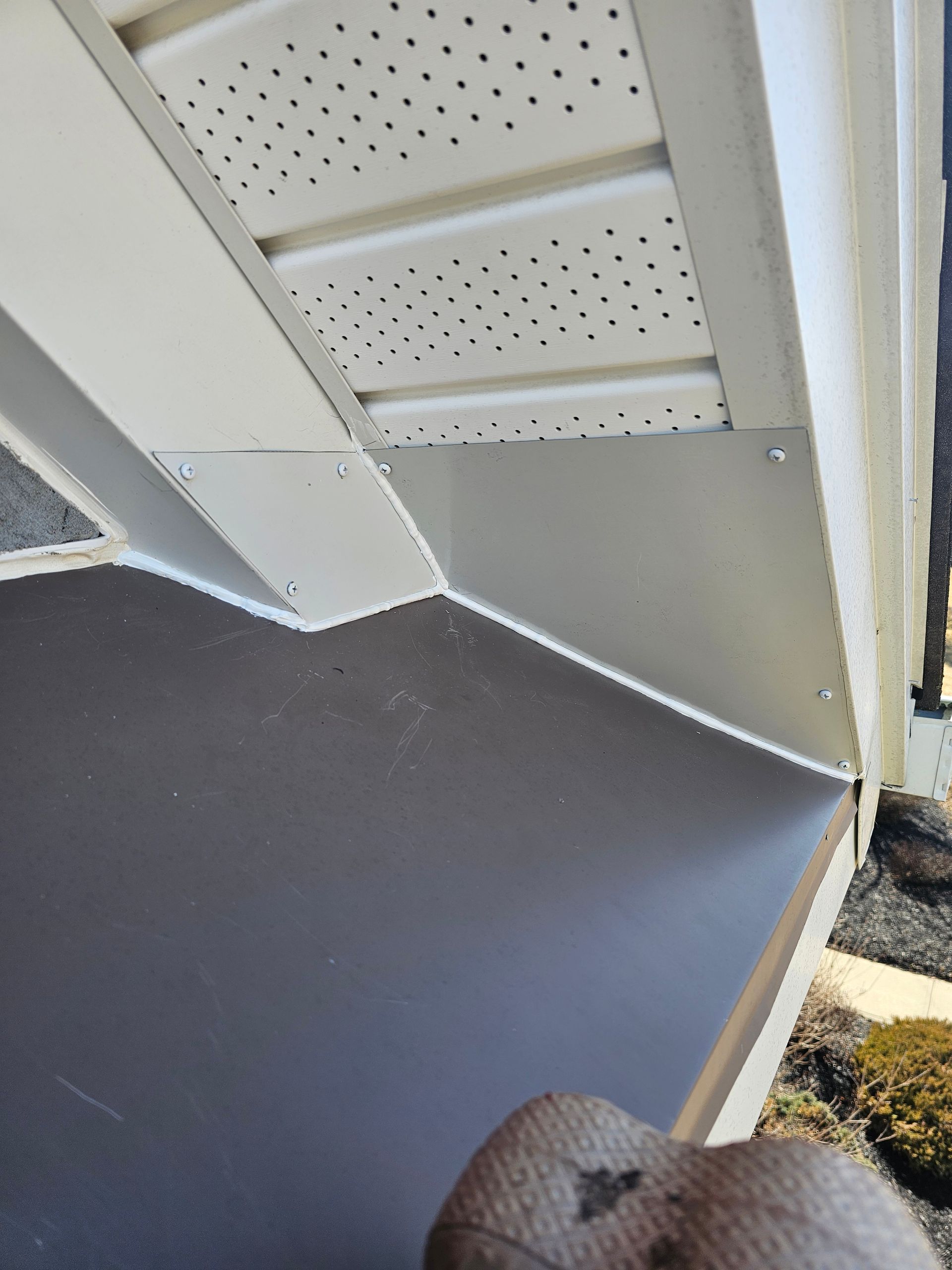 A person is holding a piece of wood under a roof.