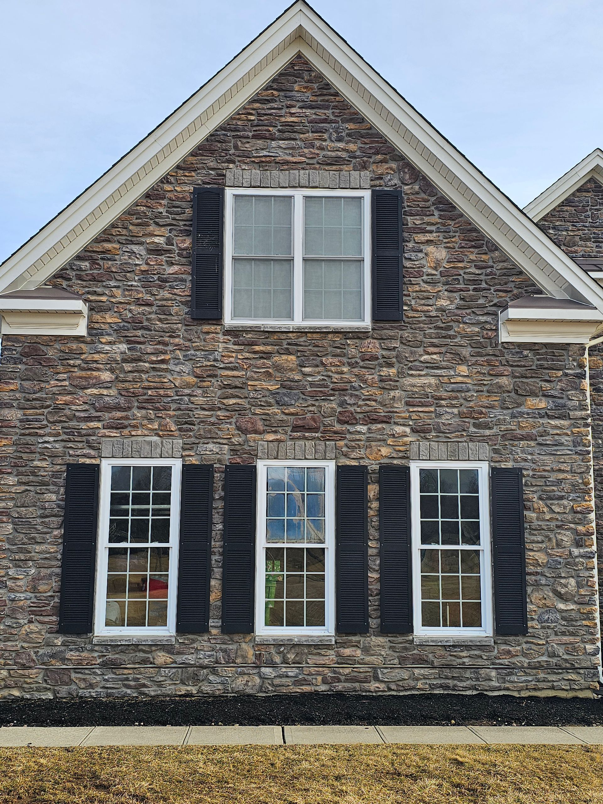 A brick house with black shutters on the windows