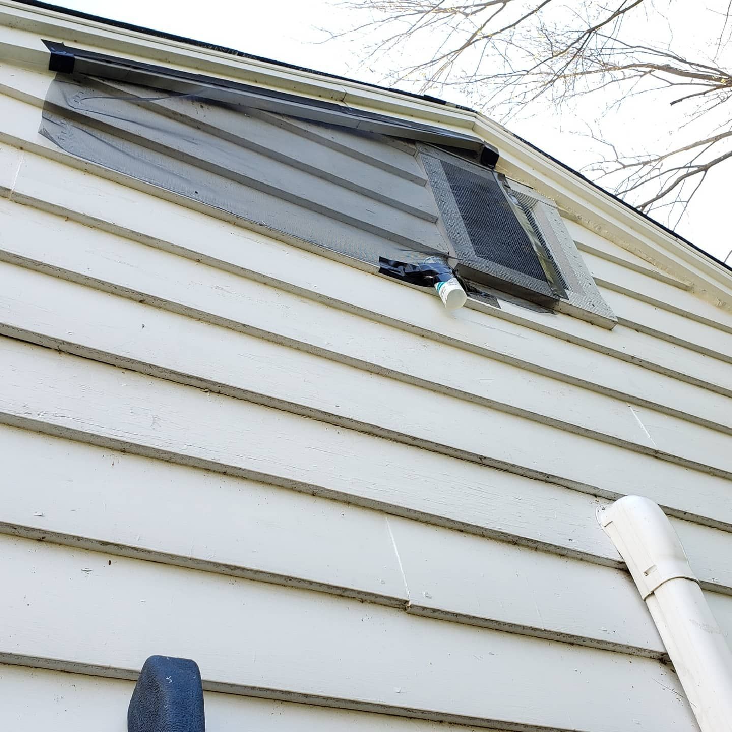 A white house with a black shutter on the roof