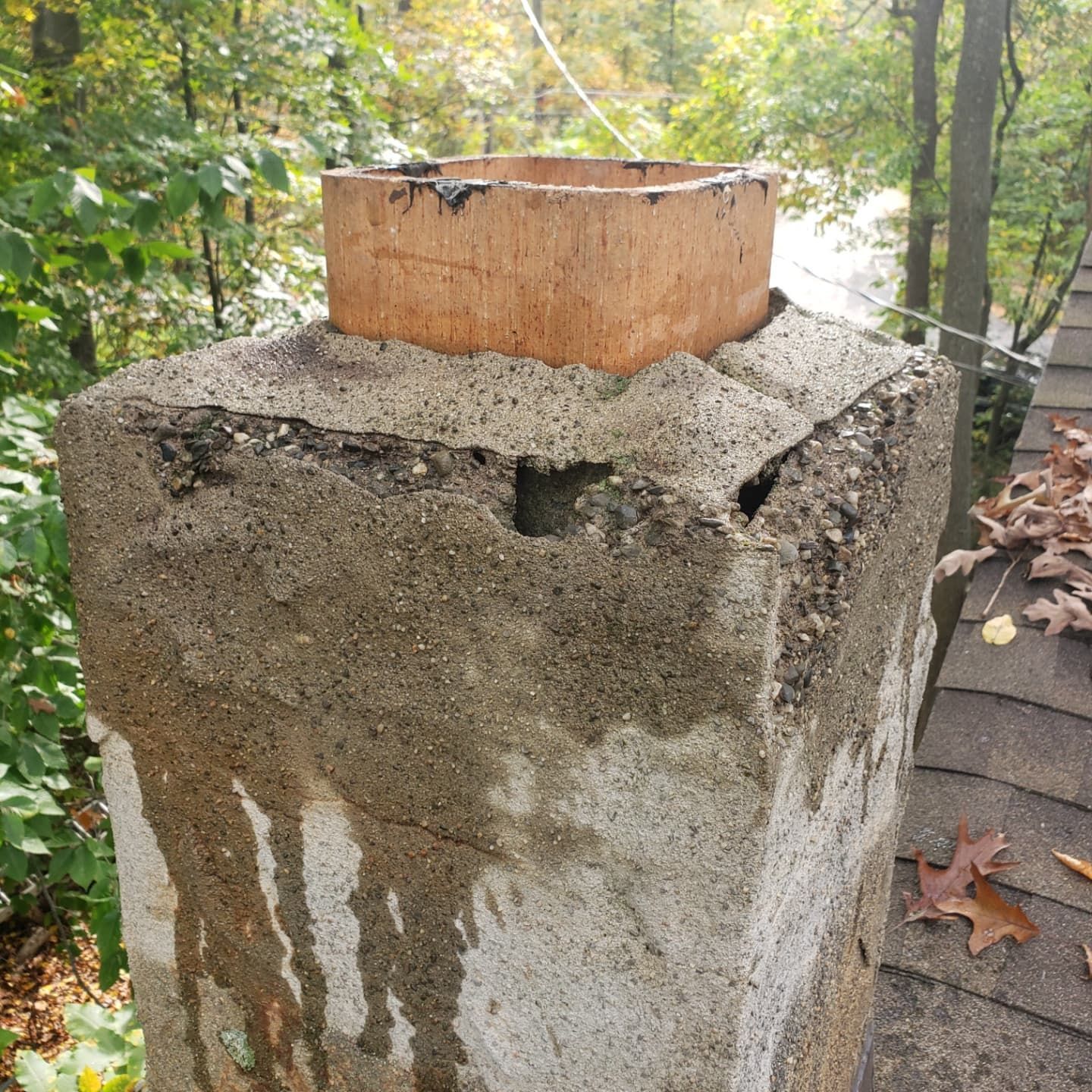A chimney with a hole in it is sitting on top of a roof.