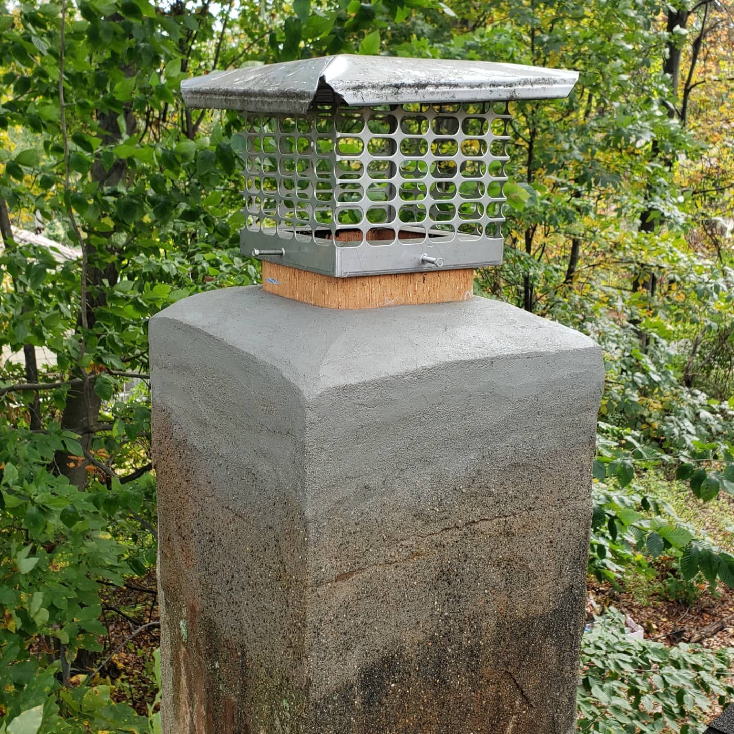 A chimney cap is sitting on top of a concrete post.