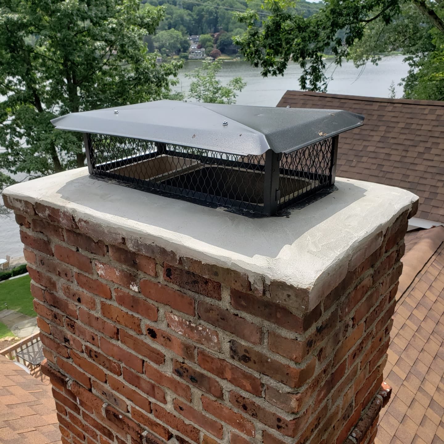 A brick chimney with a metal cover on top of it.