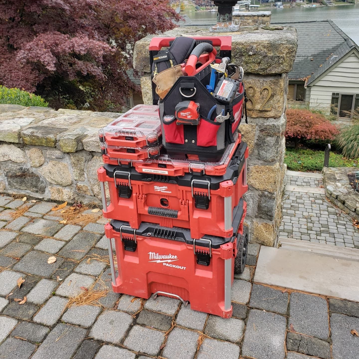 A stack of red tool boxes sitting on top of each other on a brick sidewalk.