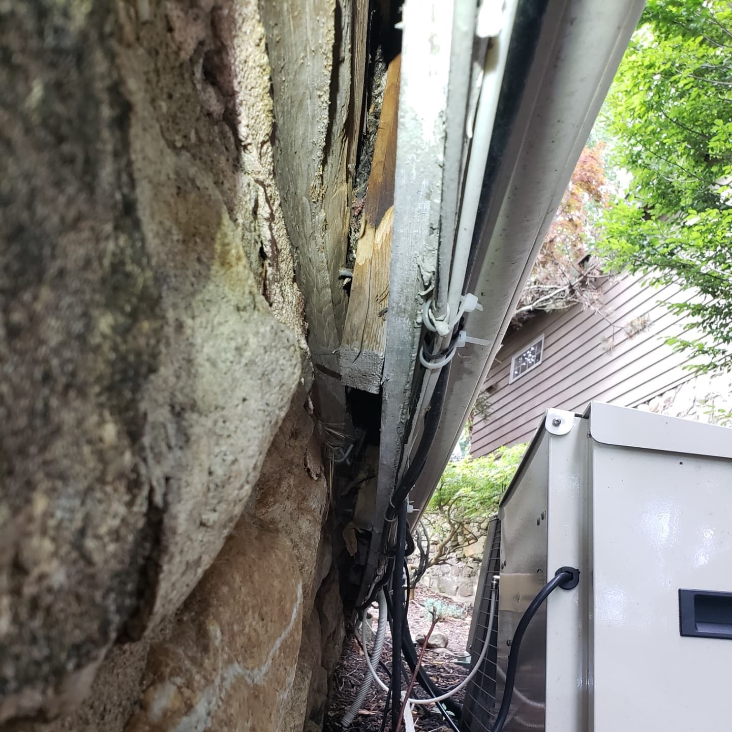 A pipe is hanging from a stone wall next to a box.