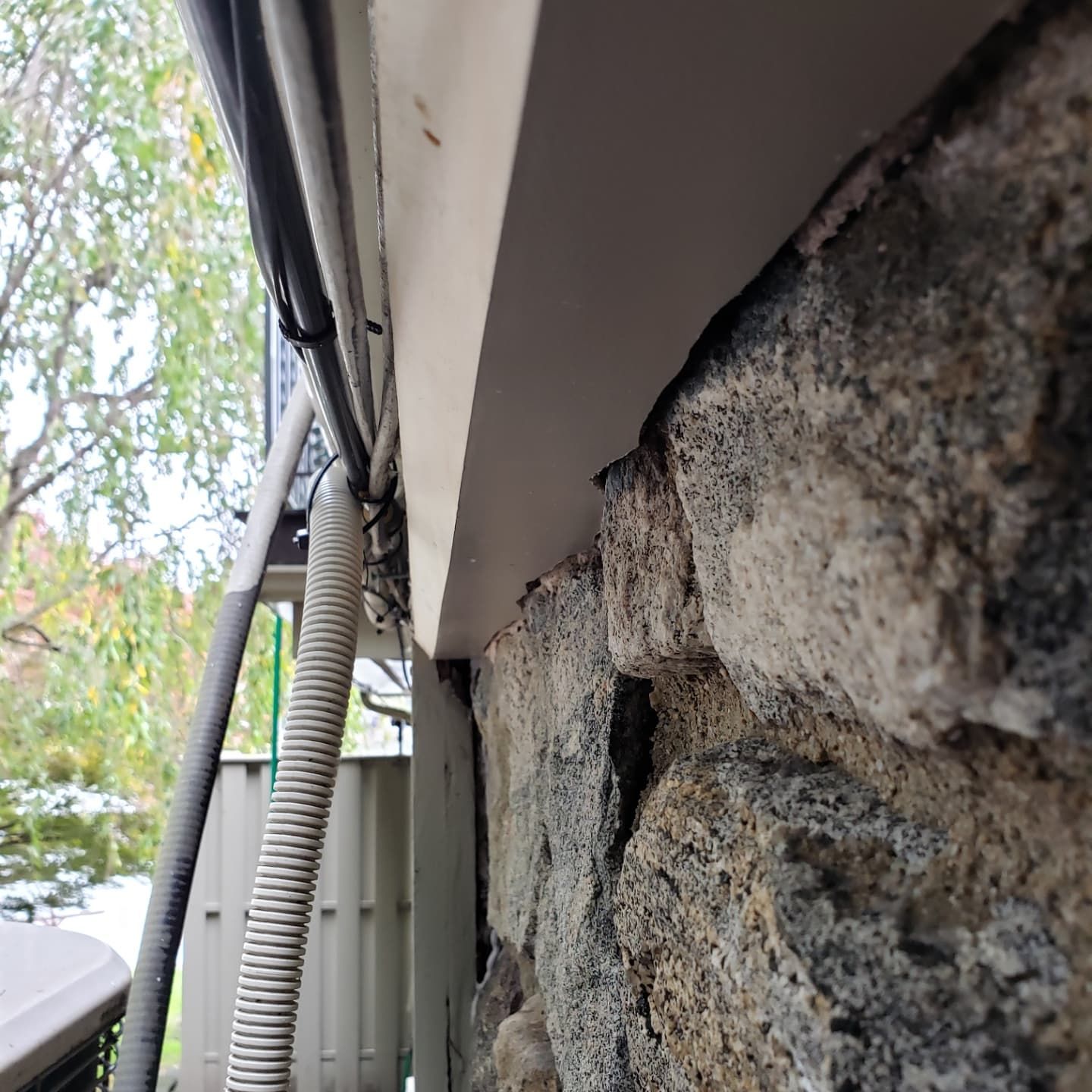 A hose is attached to the side of a stone wall