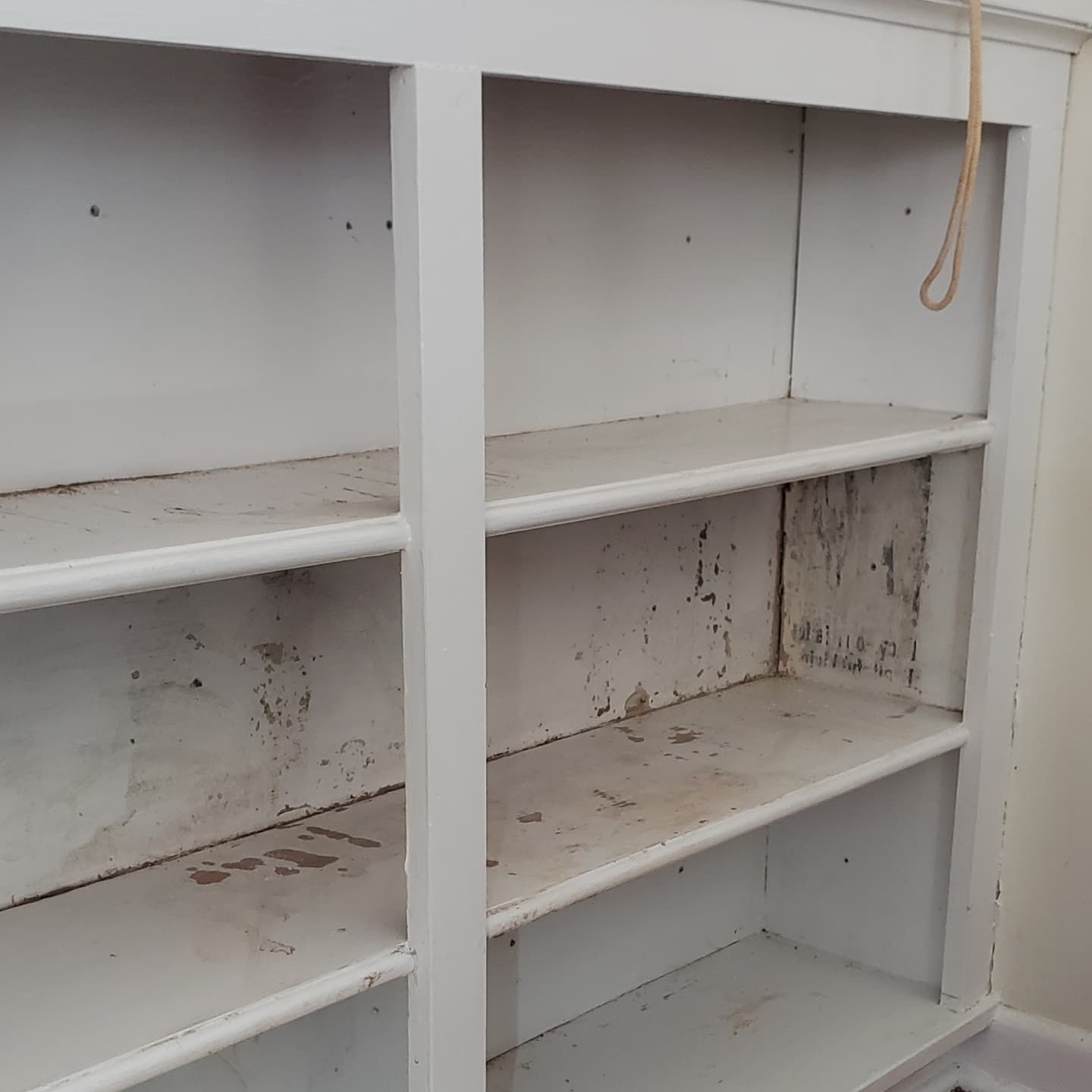 A white shelf with a rope hanging from it