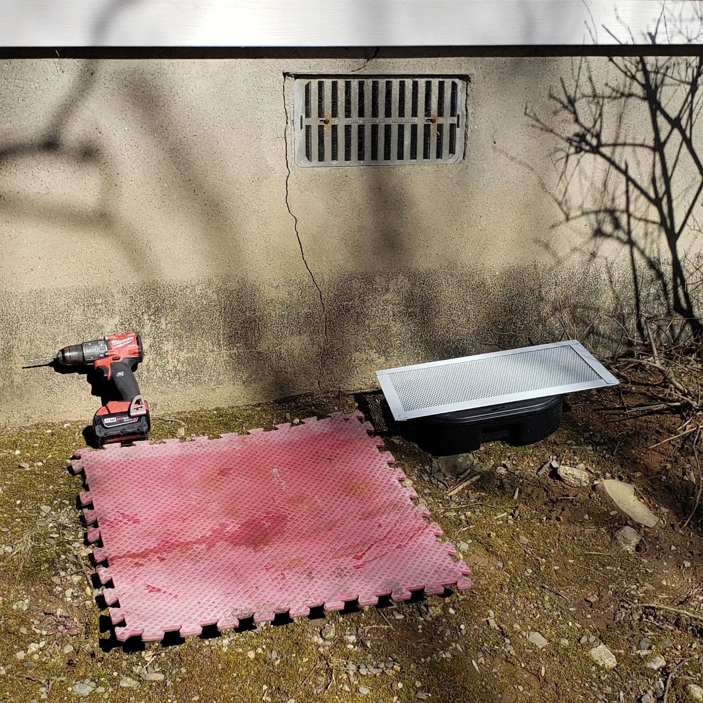 A drill is sitting on top of a red puzzle mat.