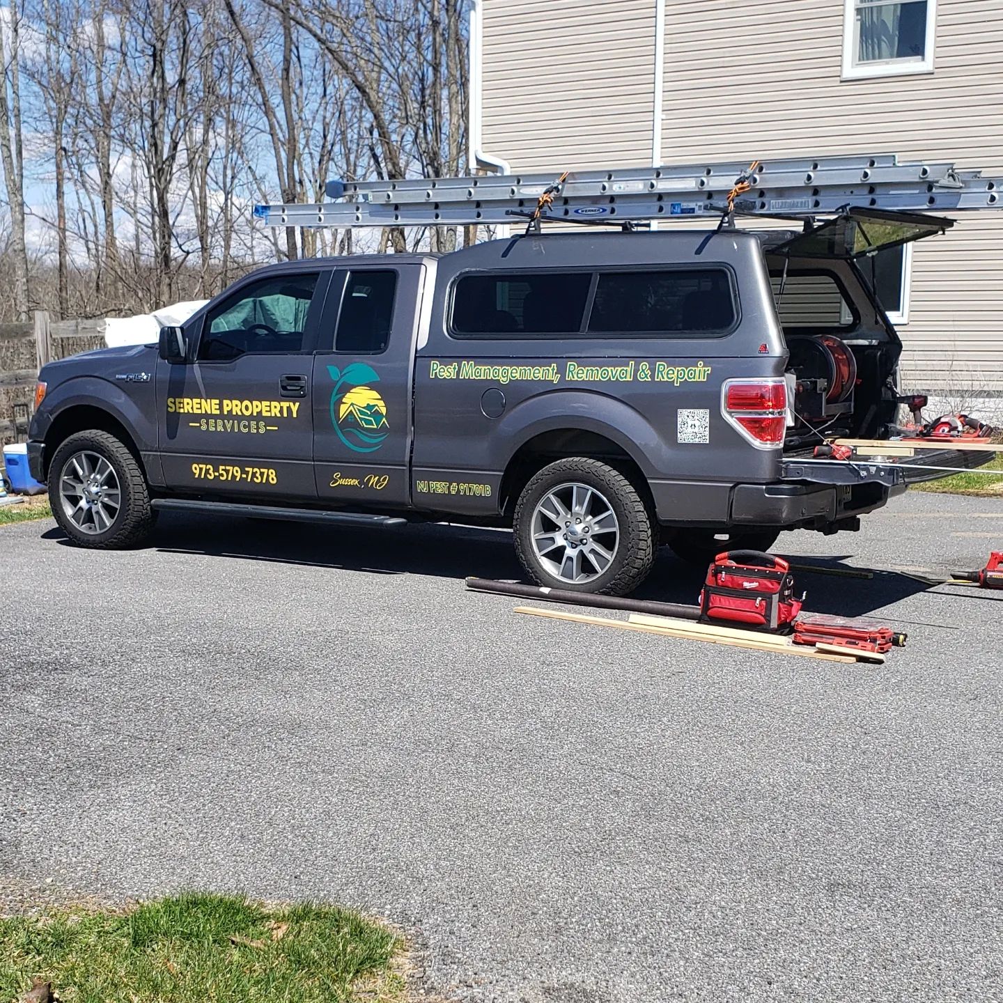 A truck with a ladder on top of it is parked in front of a house.