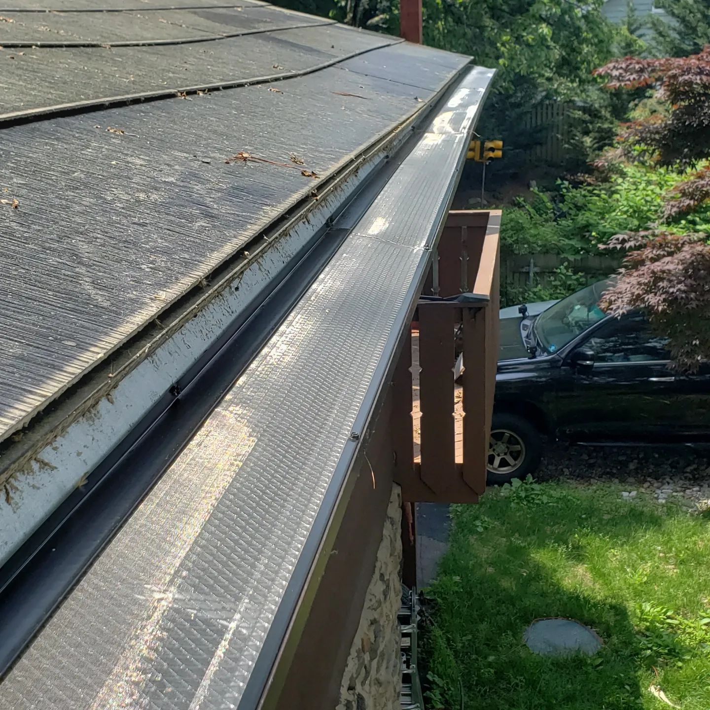 A gutter on the side of a house with a car parked in front of it