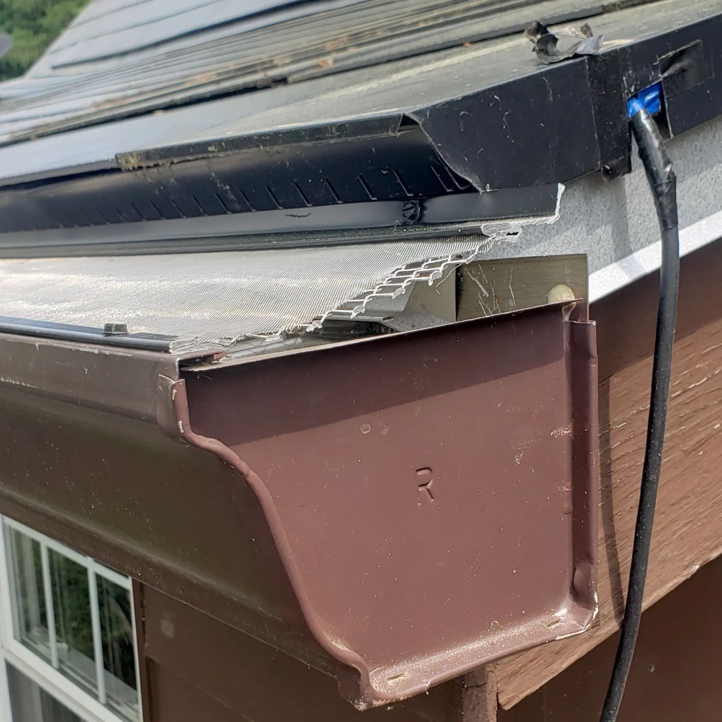 A close up of a gutter on the side of a house.